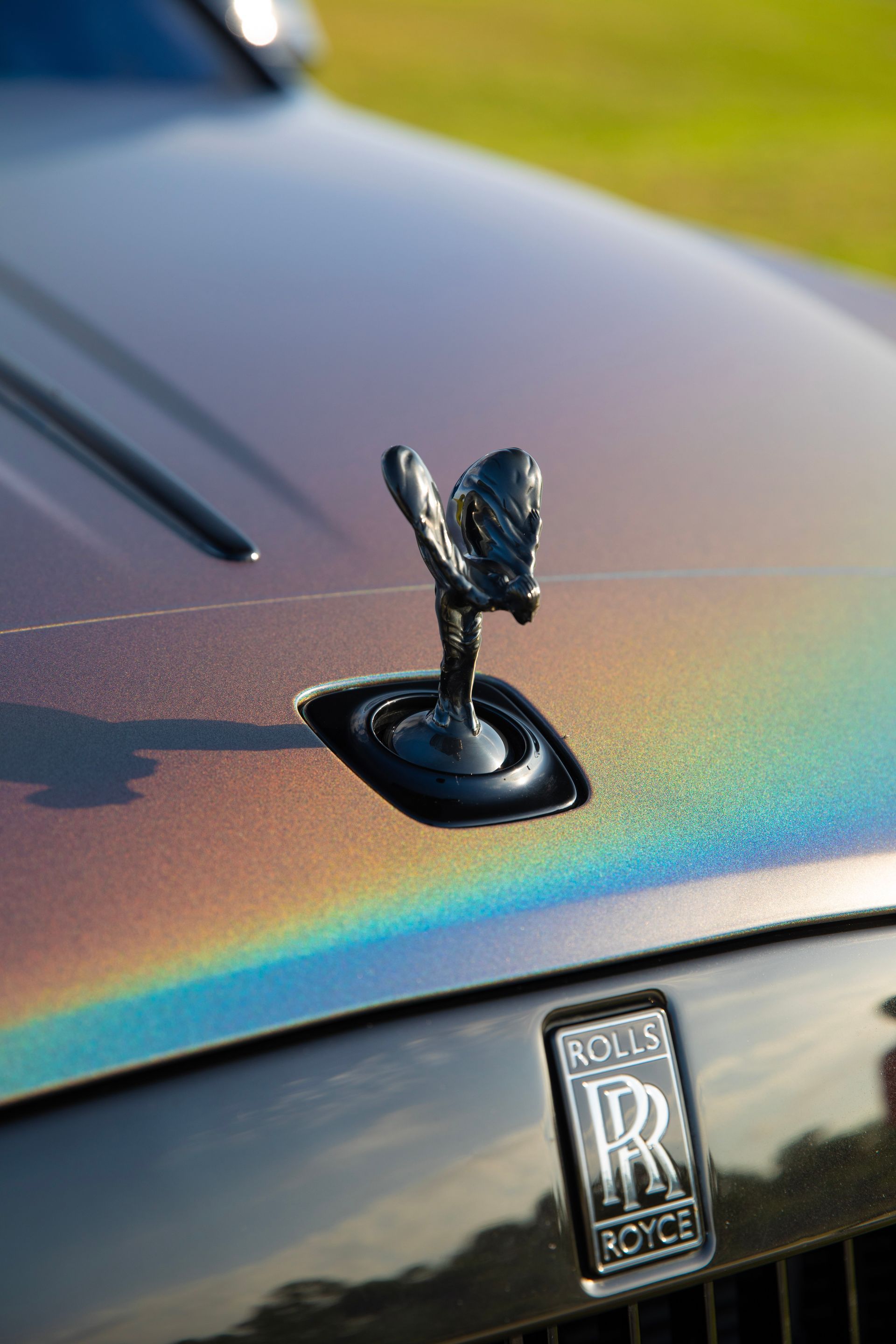 Rolls-Royce car hood with iridescent paint and black Spirit of Ecstasy hood ornament.