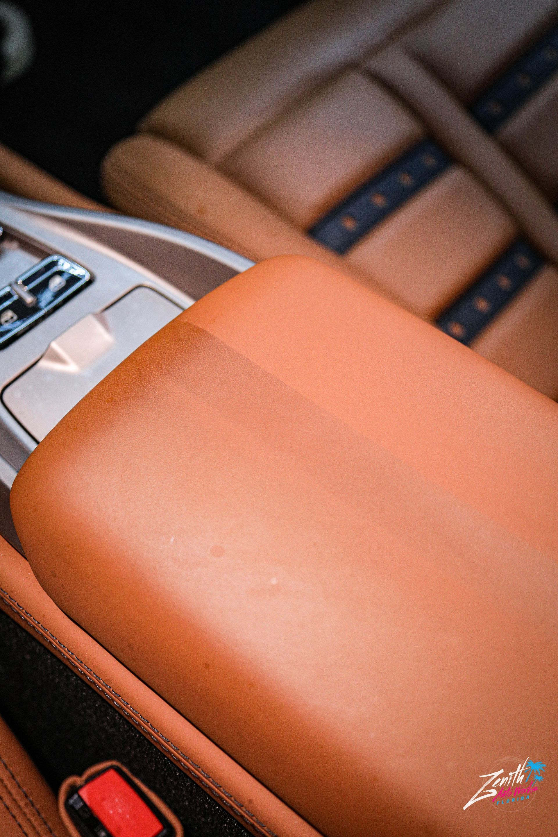 Brown leather car interior with center console armrest.