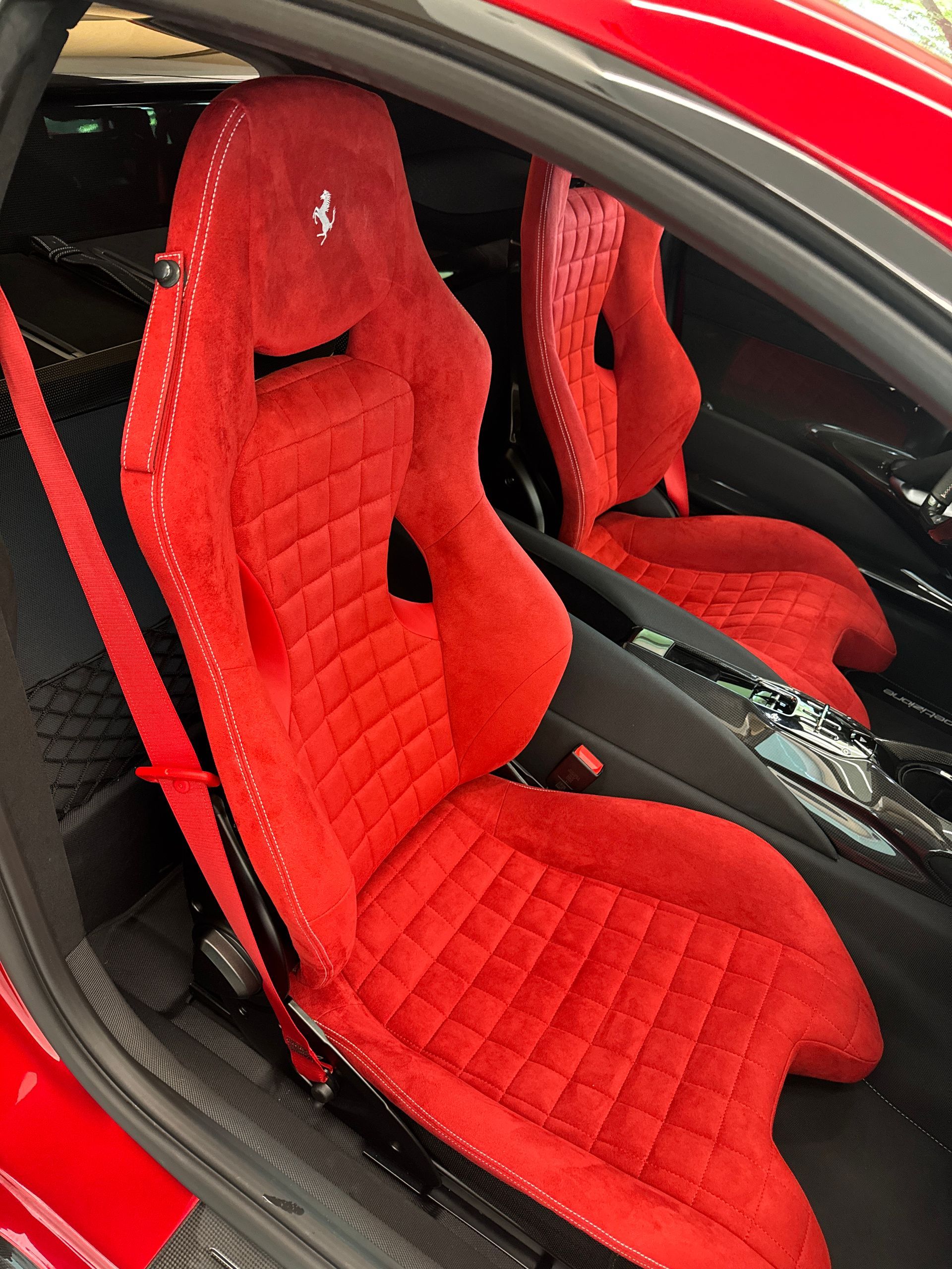 Red Ferrari car seats, quilted design, with white stitching.