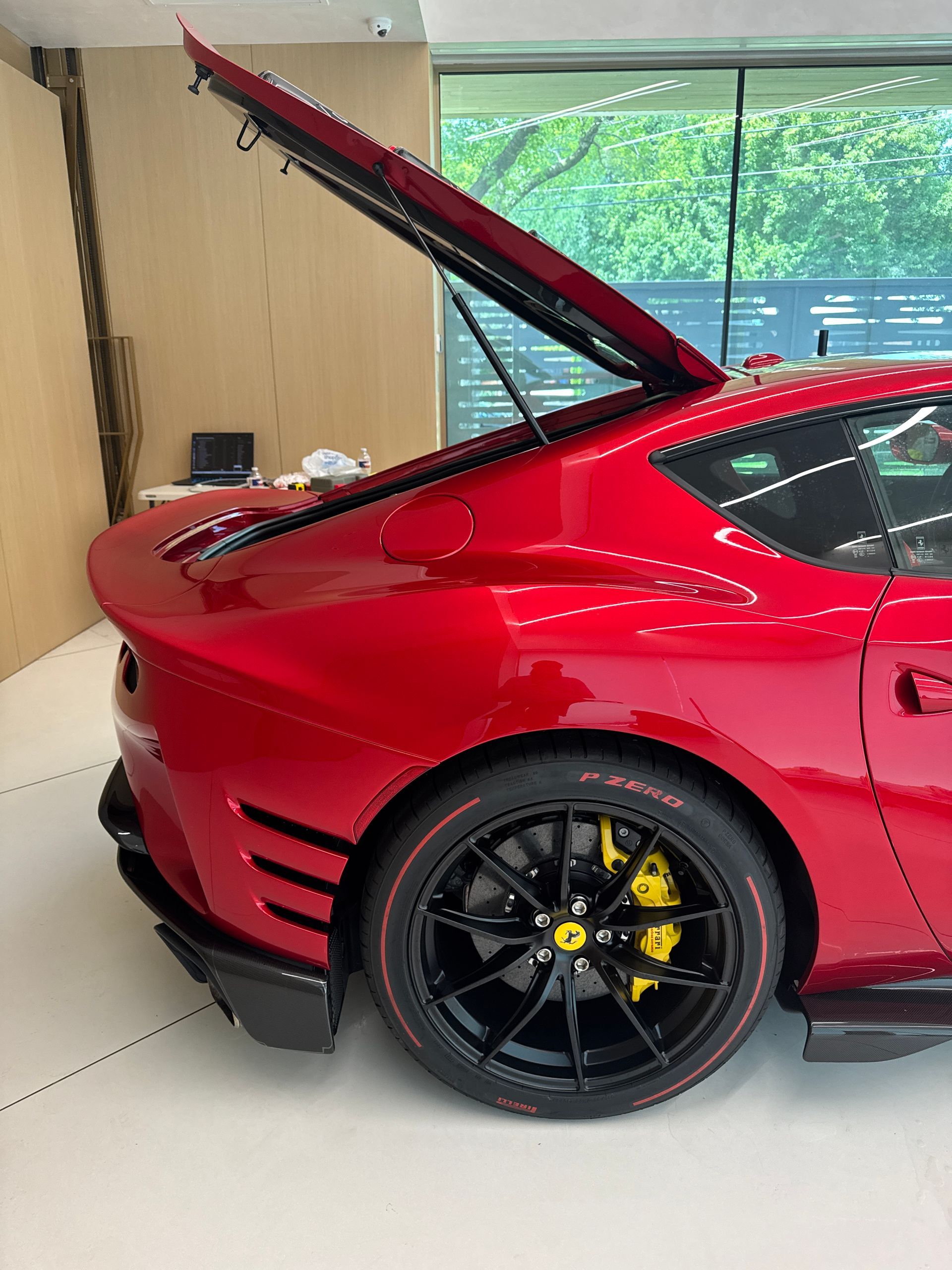 Red Ferrari with the trunk open, black wheels, and yellow brake calipers.