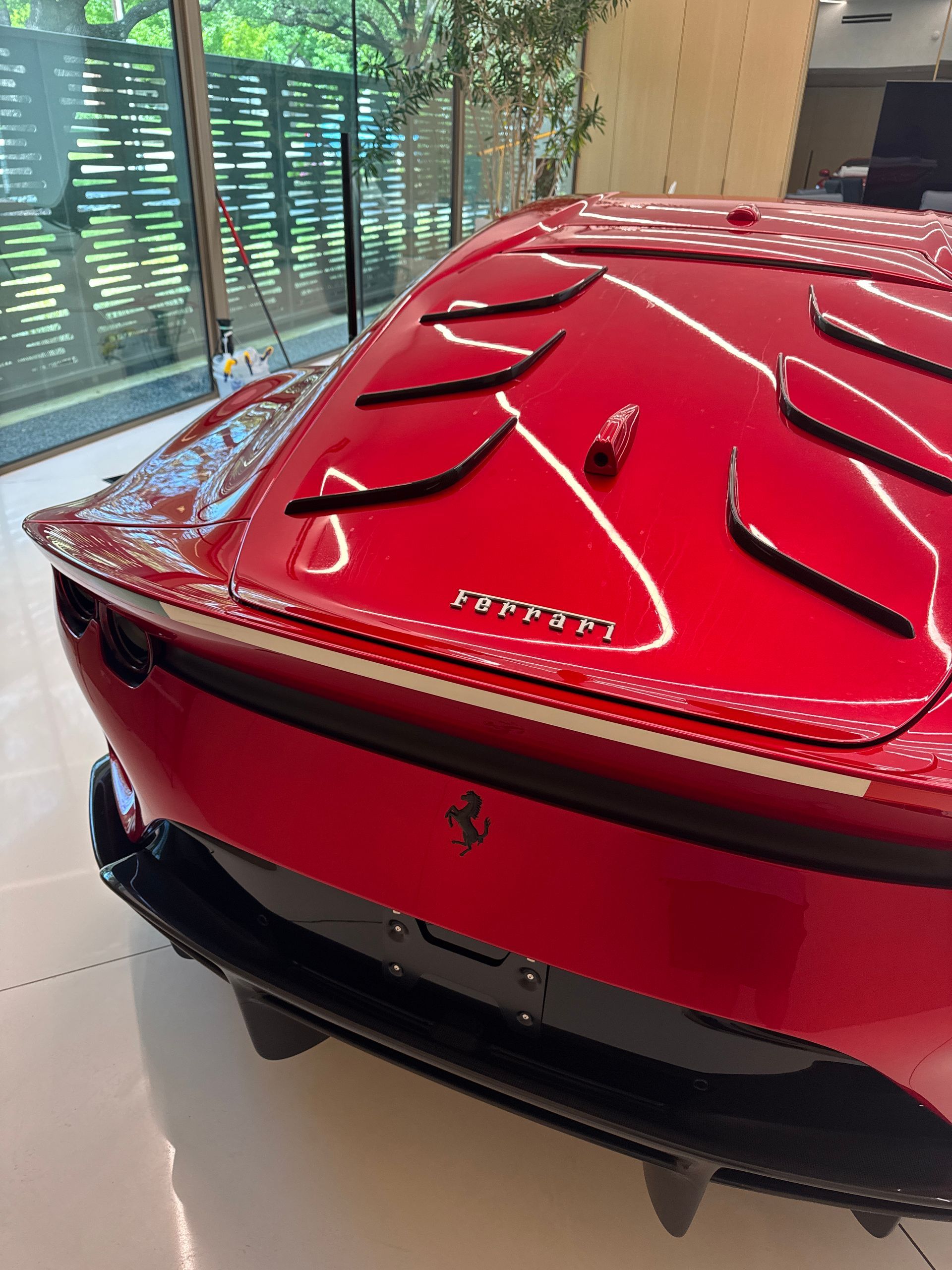 Red Ferrari rear with aerodynamic vents, black trim, and a Ferrari logo.