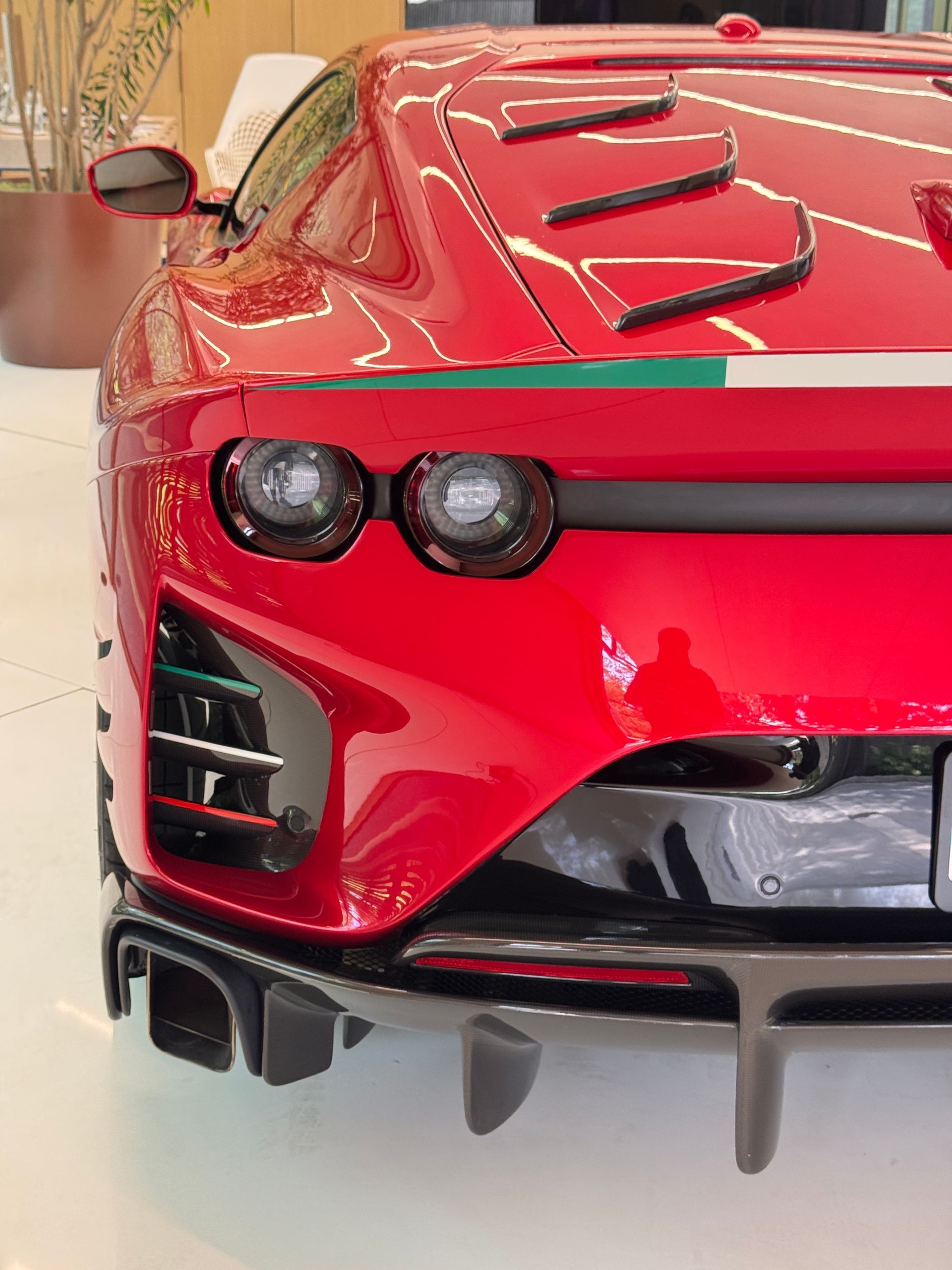 Red Ferrari sports car rear with Italian flag stripe.