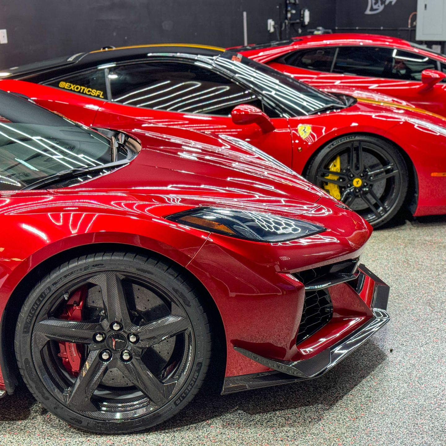 Red Saleen S7 sports car with gull-wing doors open, parked in a lot under a clear, blue sky.