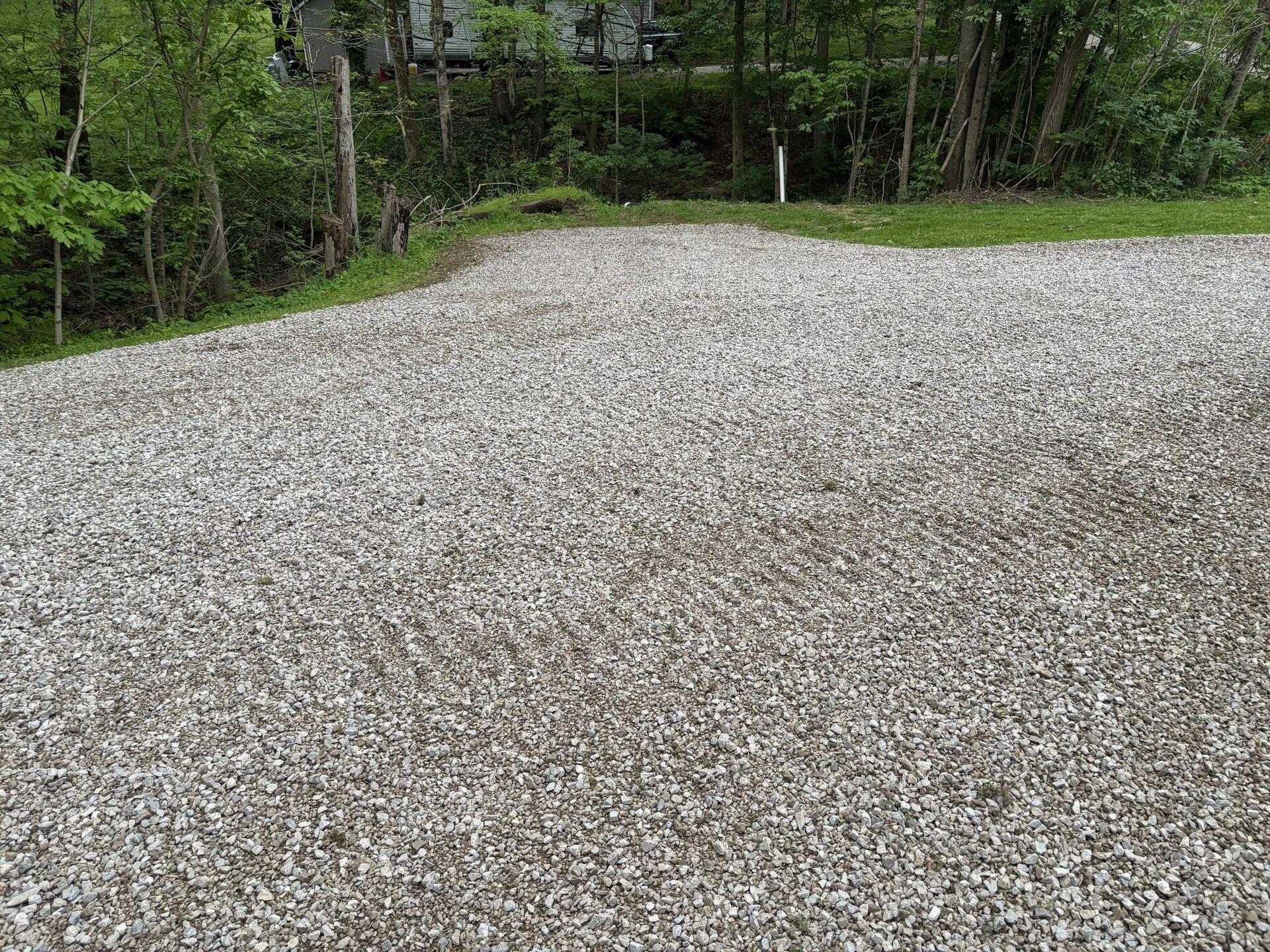 Gravel driveway beside dense green trees and brush