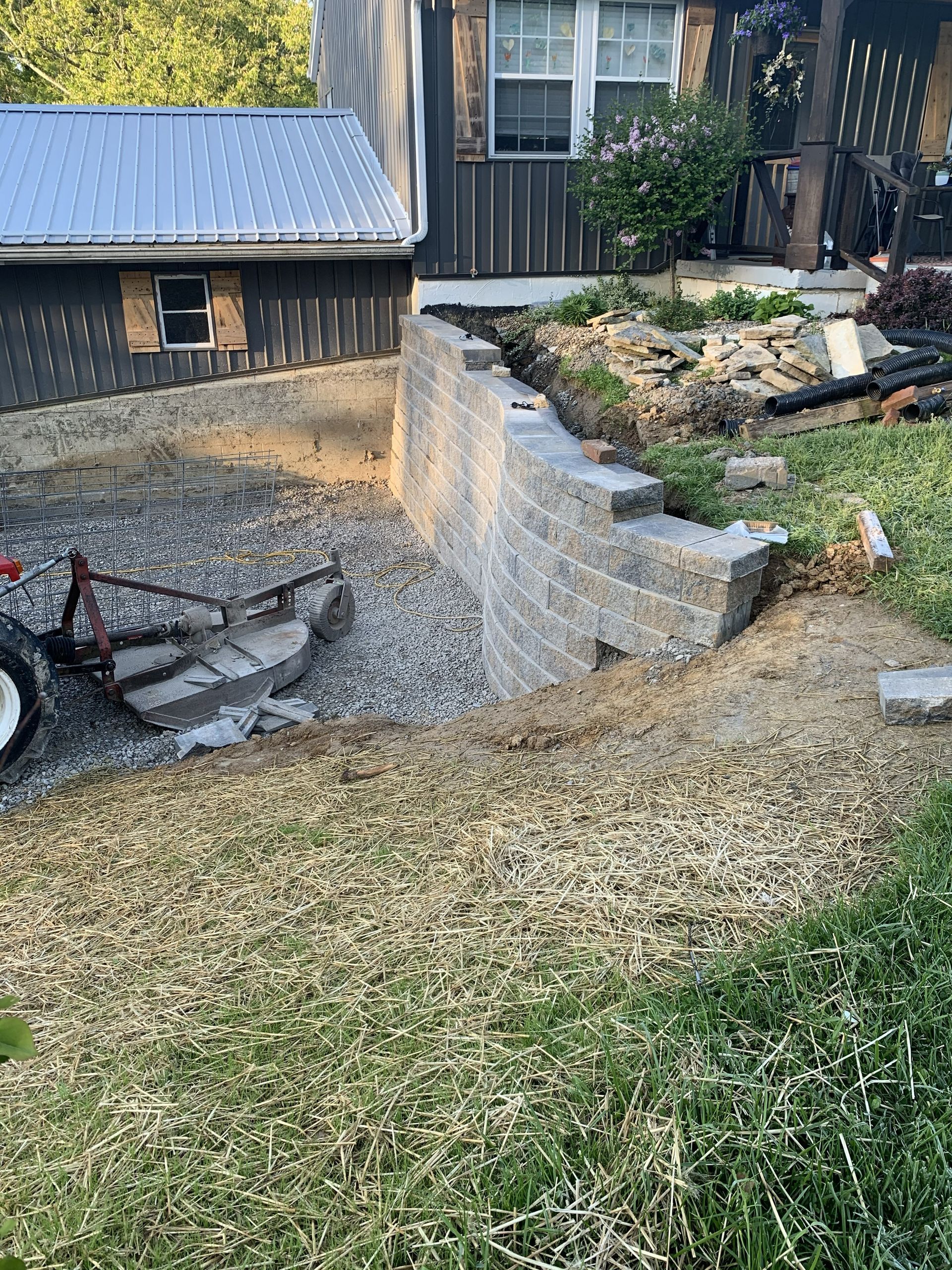 Backyard retaining wall and gravel ramp beside a house, with a red wagon on the left.