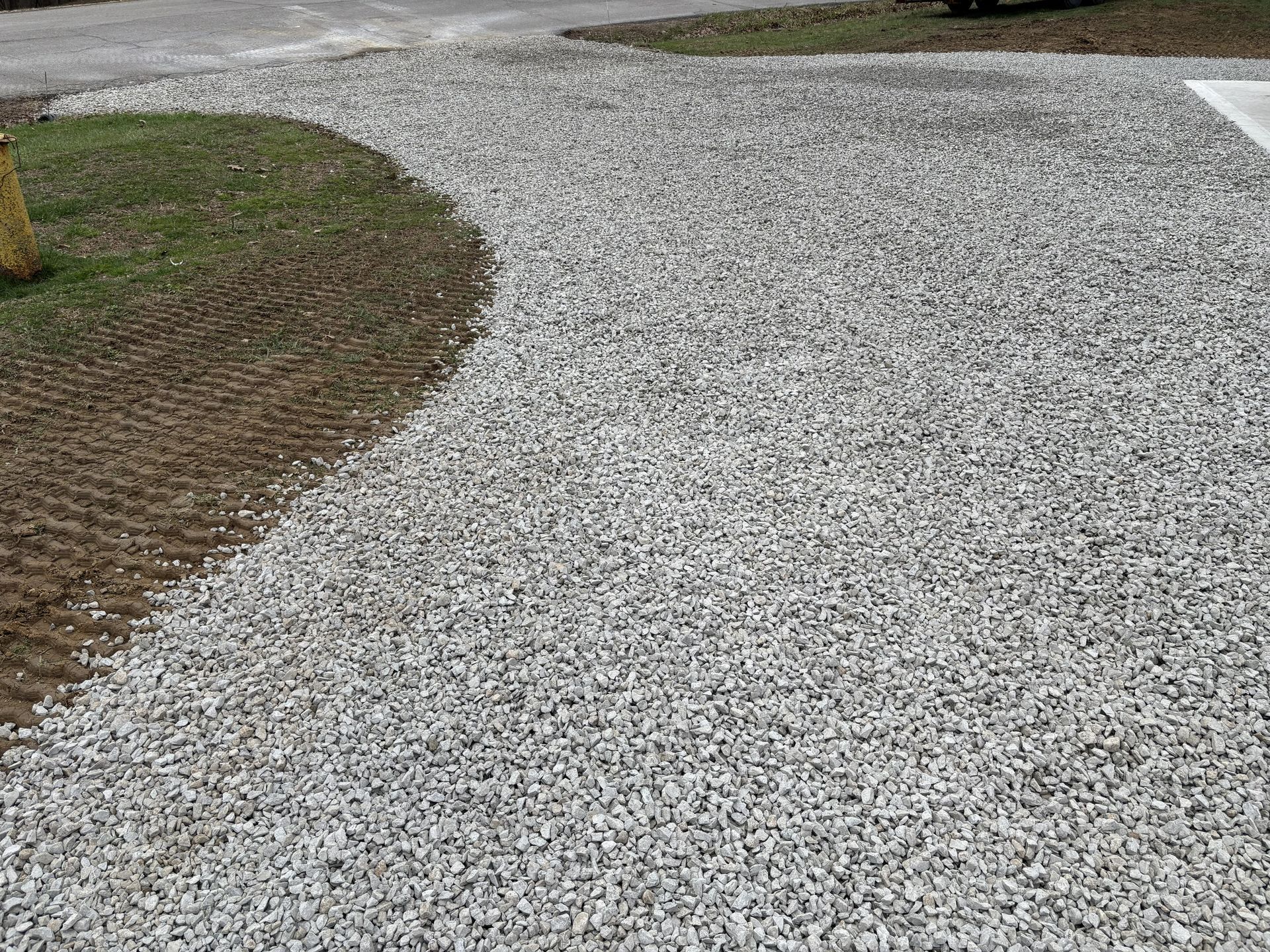Curved gravel driveway beside a patch of grass and soil