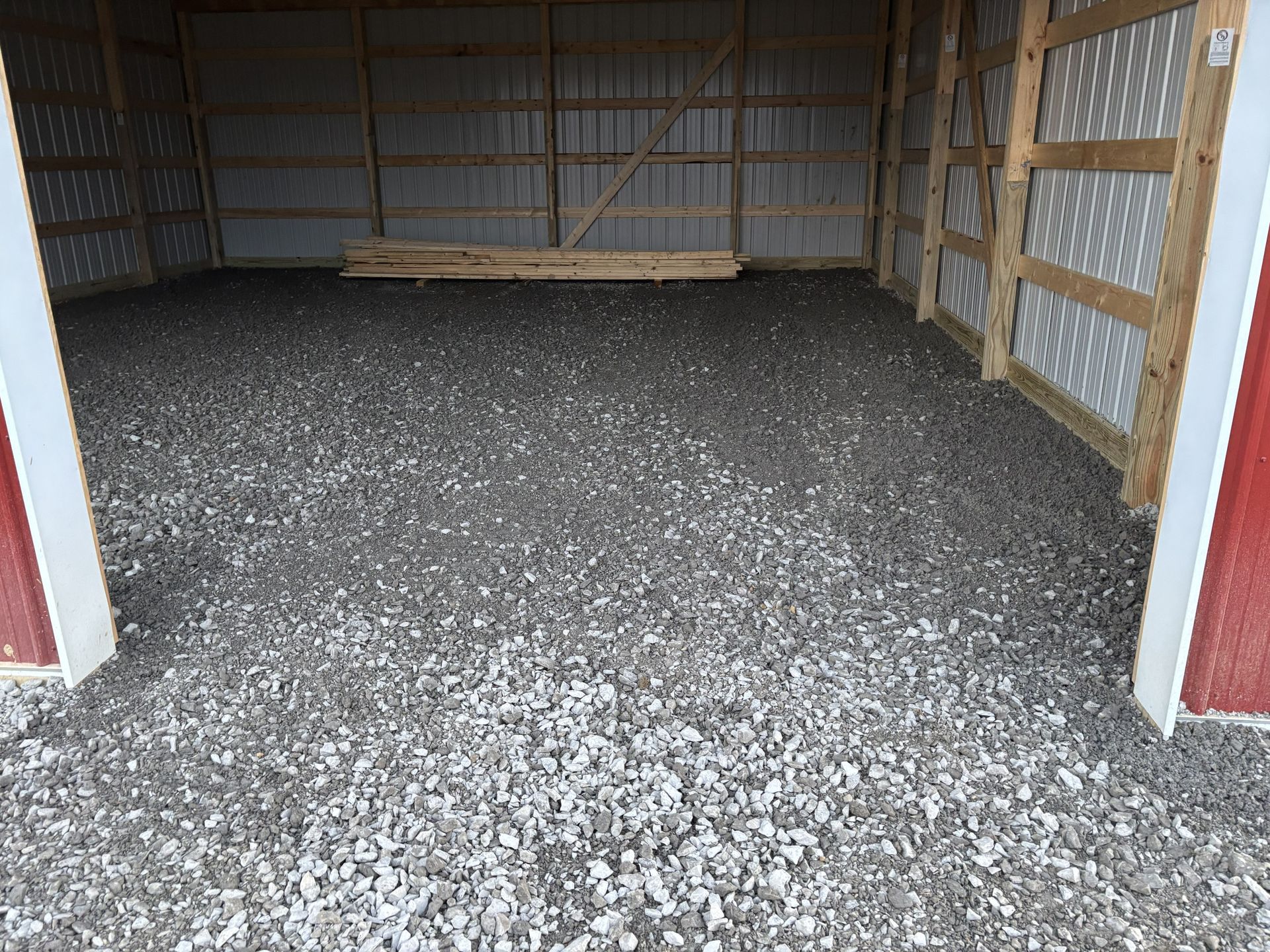 Empty gravel-floored shed with wooden walls and an open front