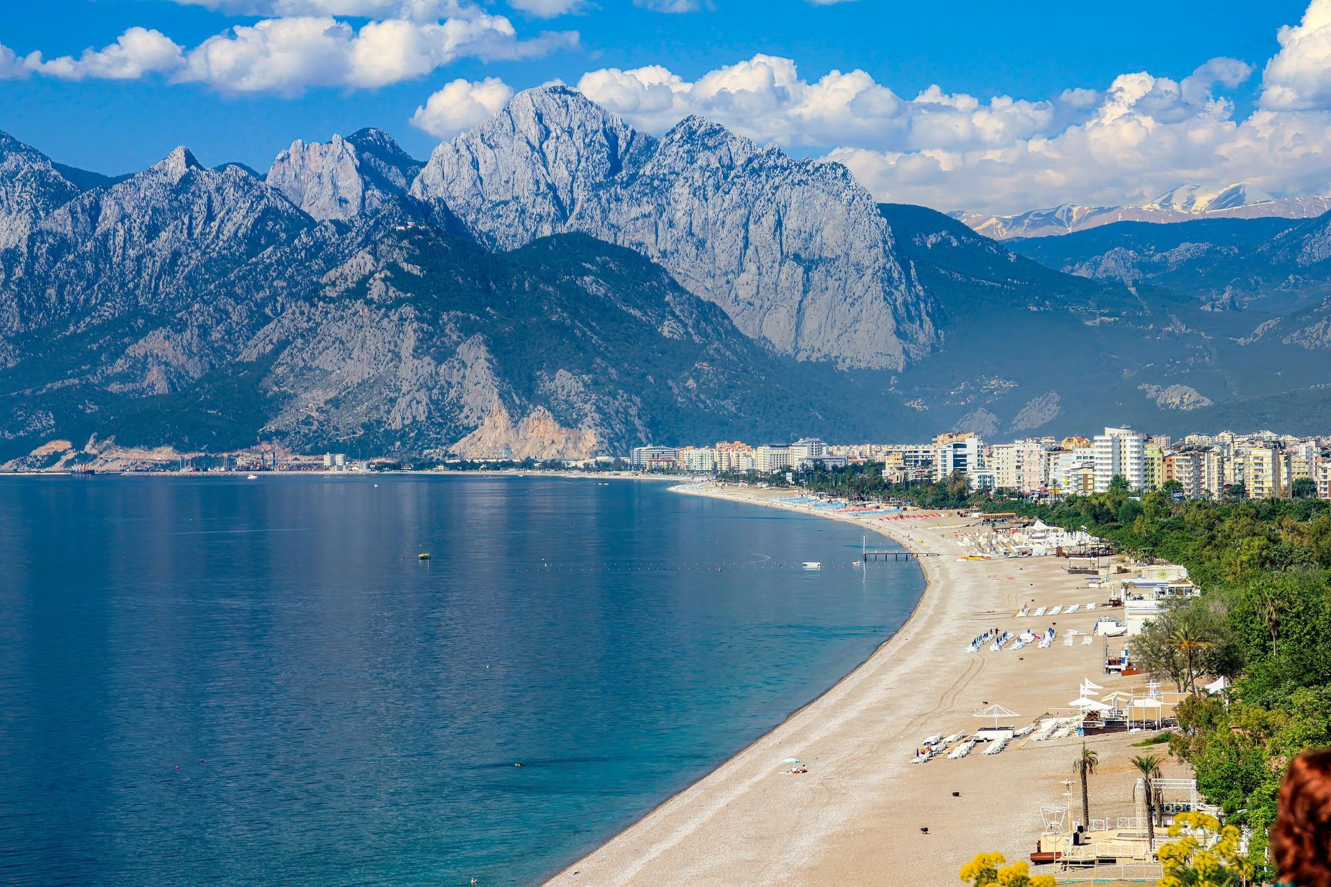 Mountain bay with blue sea, sandy beach, and rocky cliffs under a clear sky