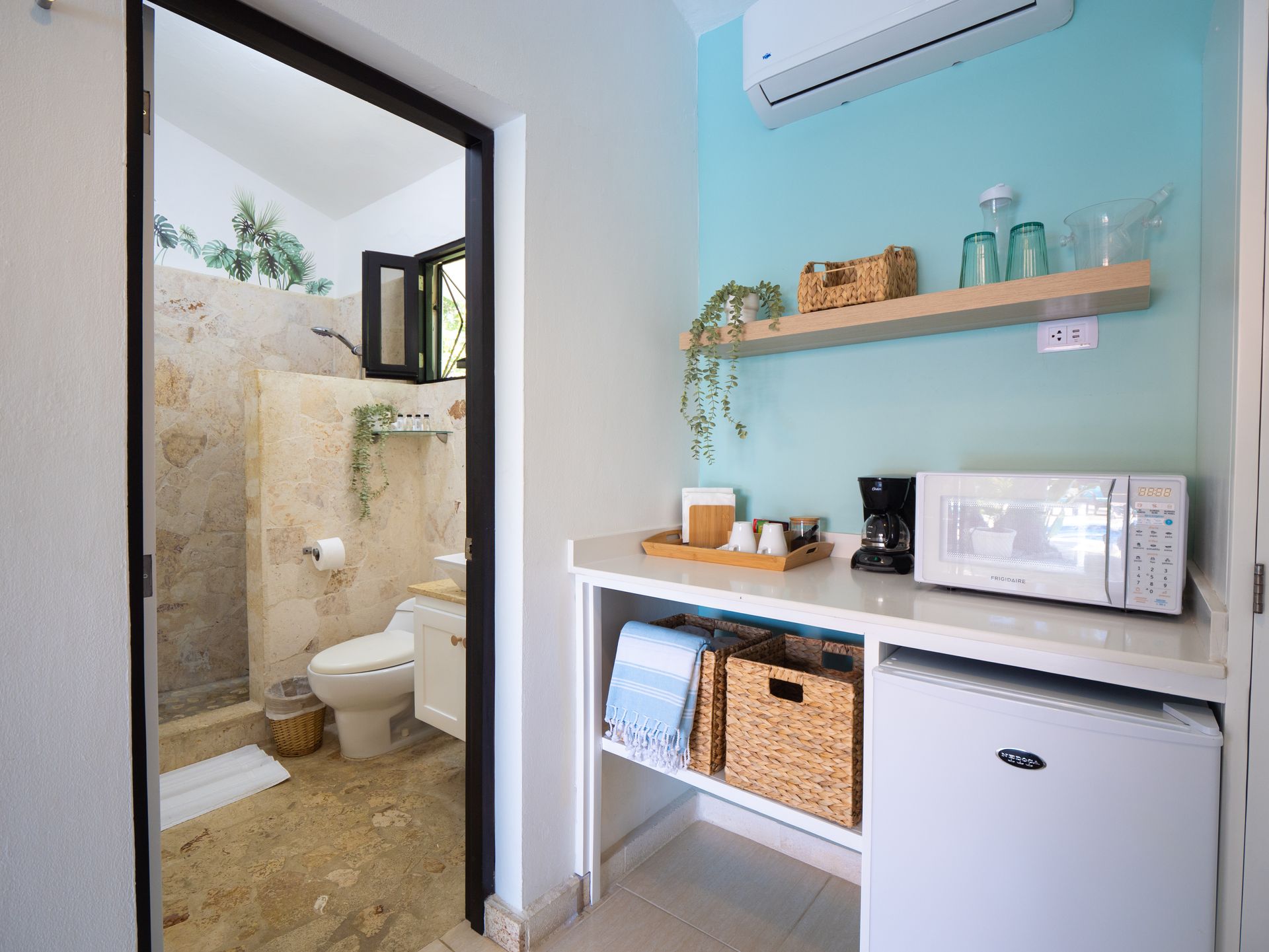 A small hotel room with a kitchenette and an open door to the bathroom.