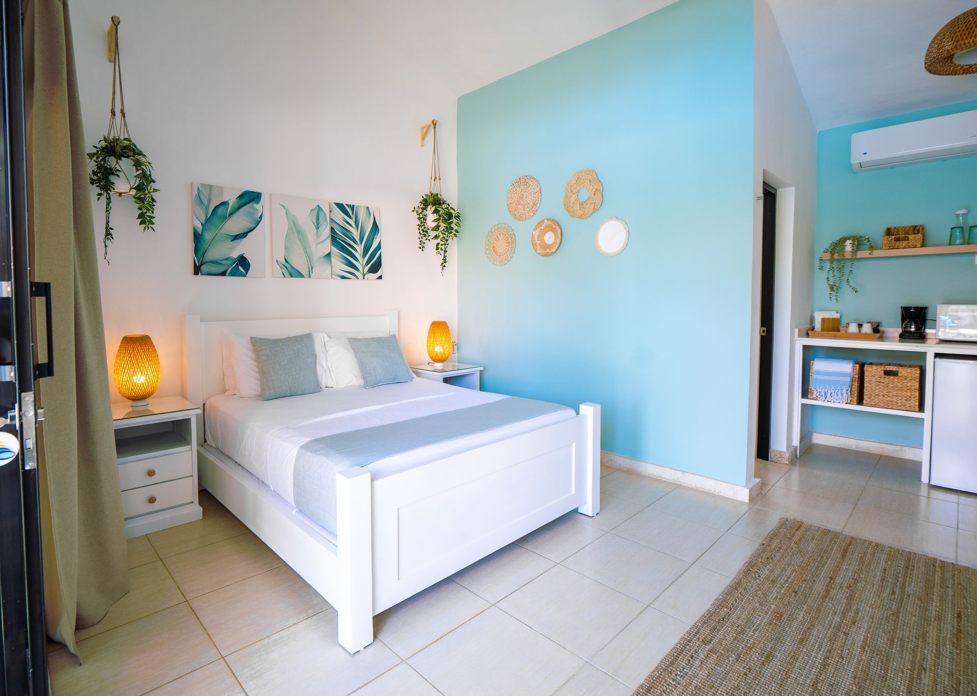 Bright bedroom with white bed, blue wall, woven decor, and hanging plants.