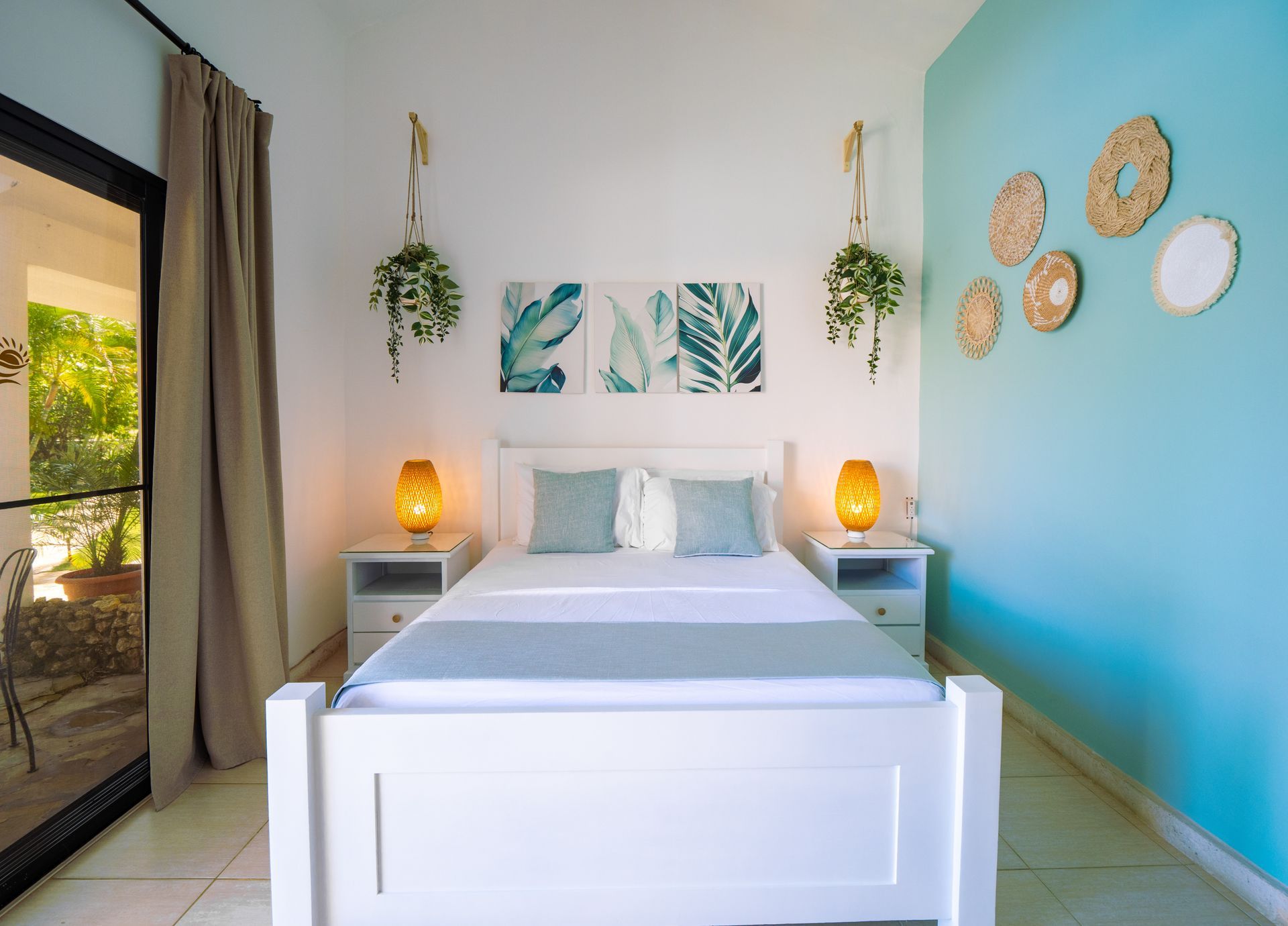 Bedroom with white bed, teal accent wall, plants, and bedside lamps.