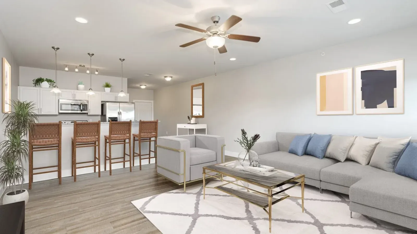Bright open-concept living room with gray sofa, coffee table, and kitchen with bar stools and pendant lights.