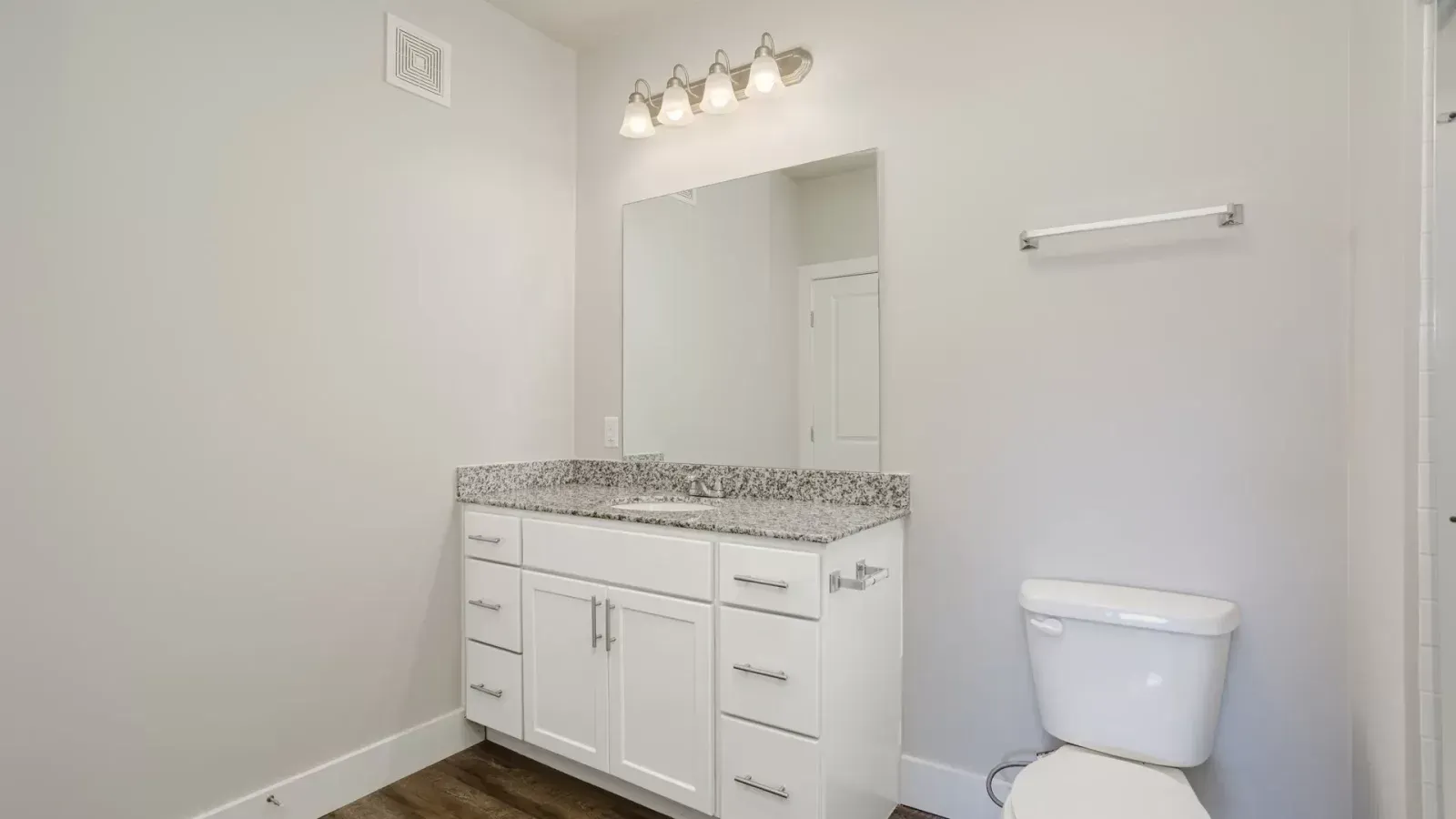 Bathroom with white vanity, tiled backsplash, mirror, towel bar, and toilet on the right