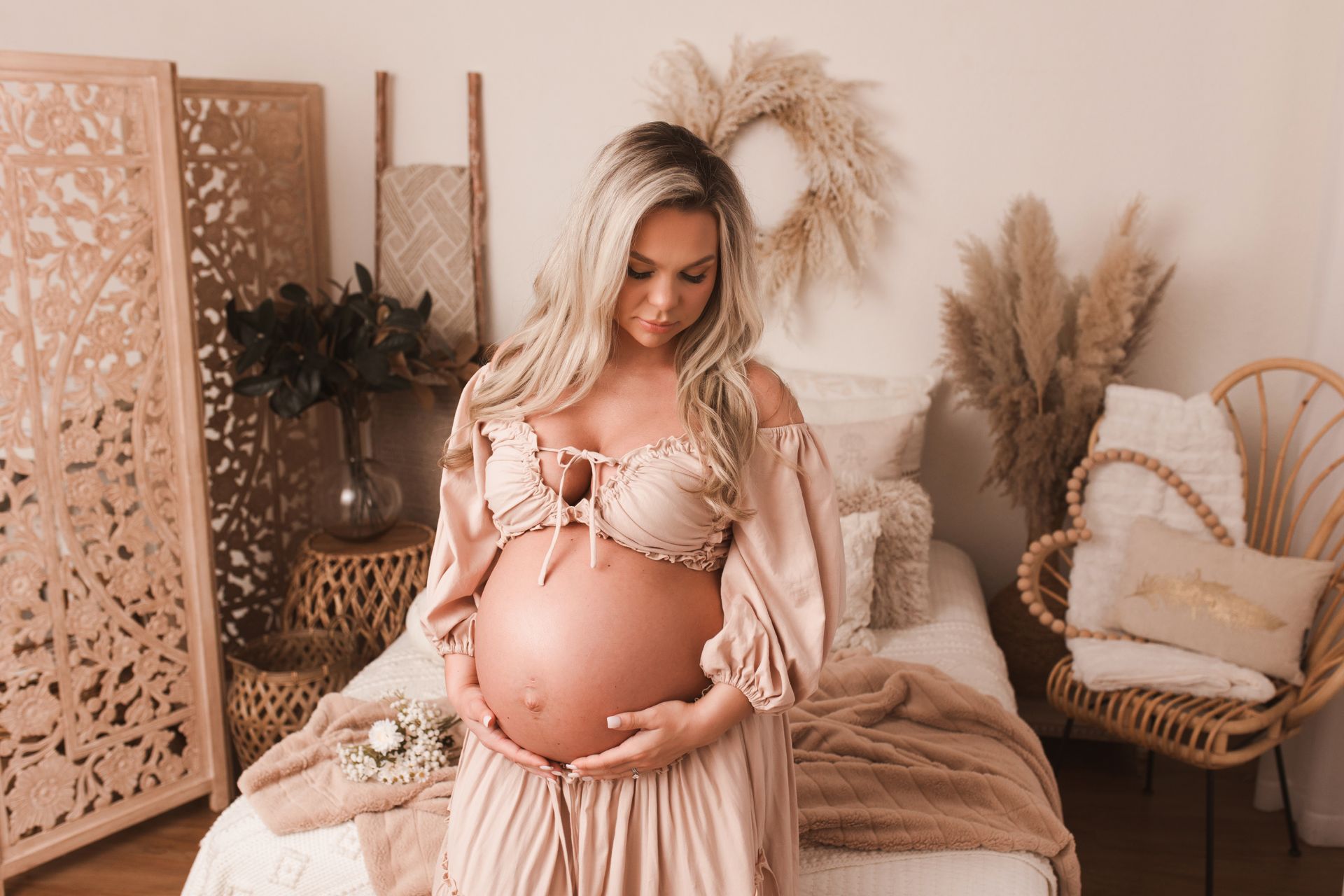 A pregnant woman wrapped in a white cloth is holding her belly.