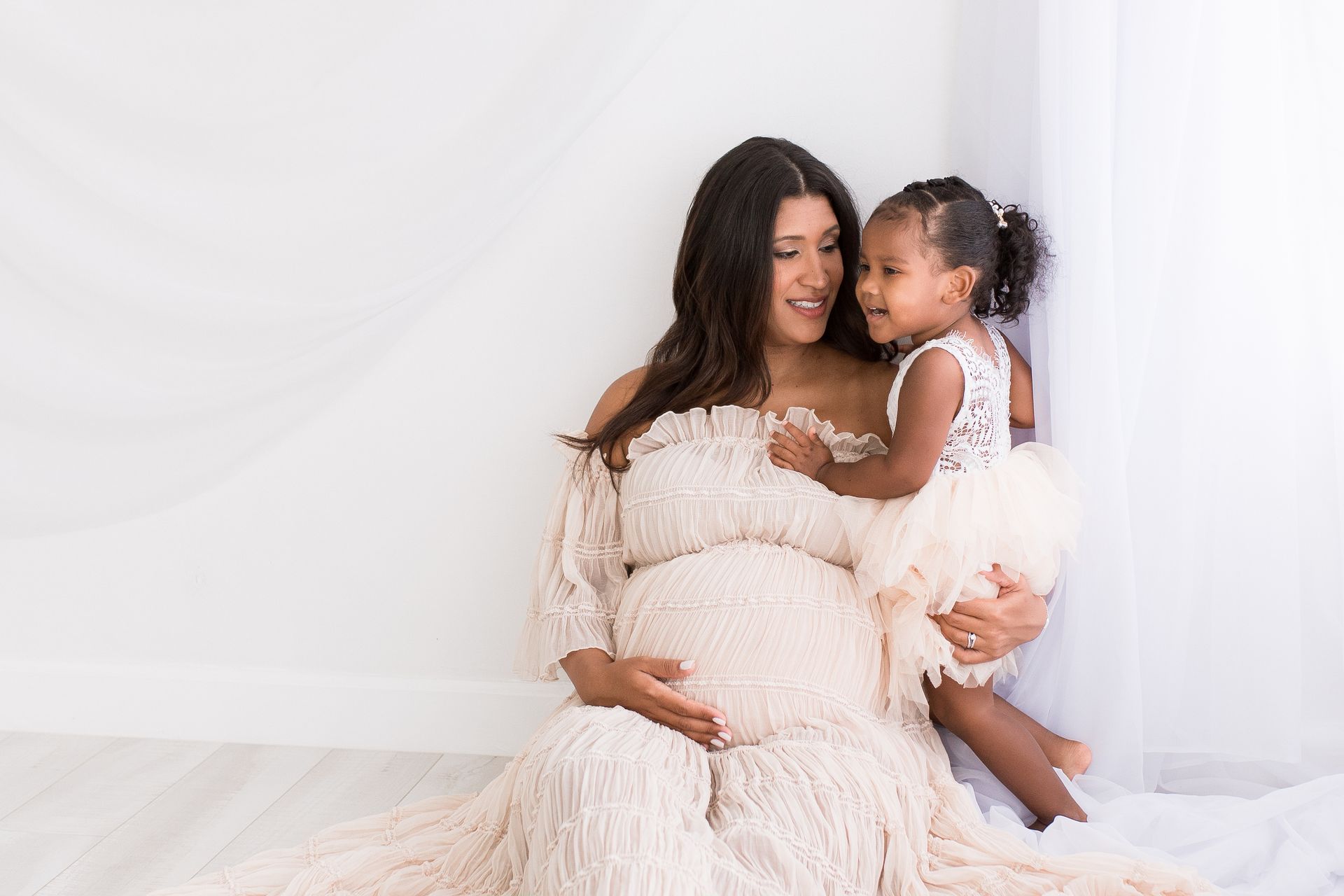 A pregnant woman in a pink dress is holding her belly.