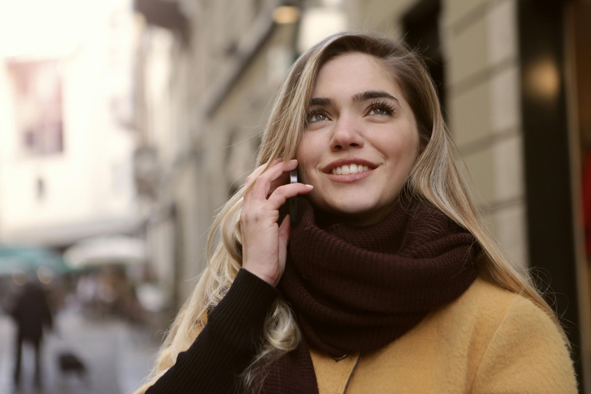 A woman wearing a scarf is talking on a cell phone.