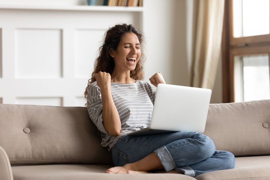 A woman is sitting on a couch using a laptop computer.