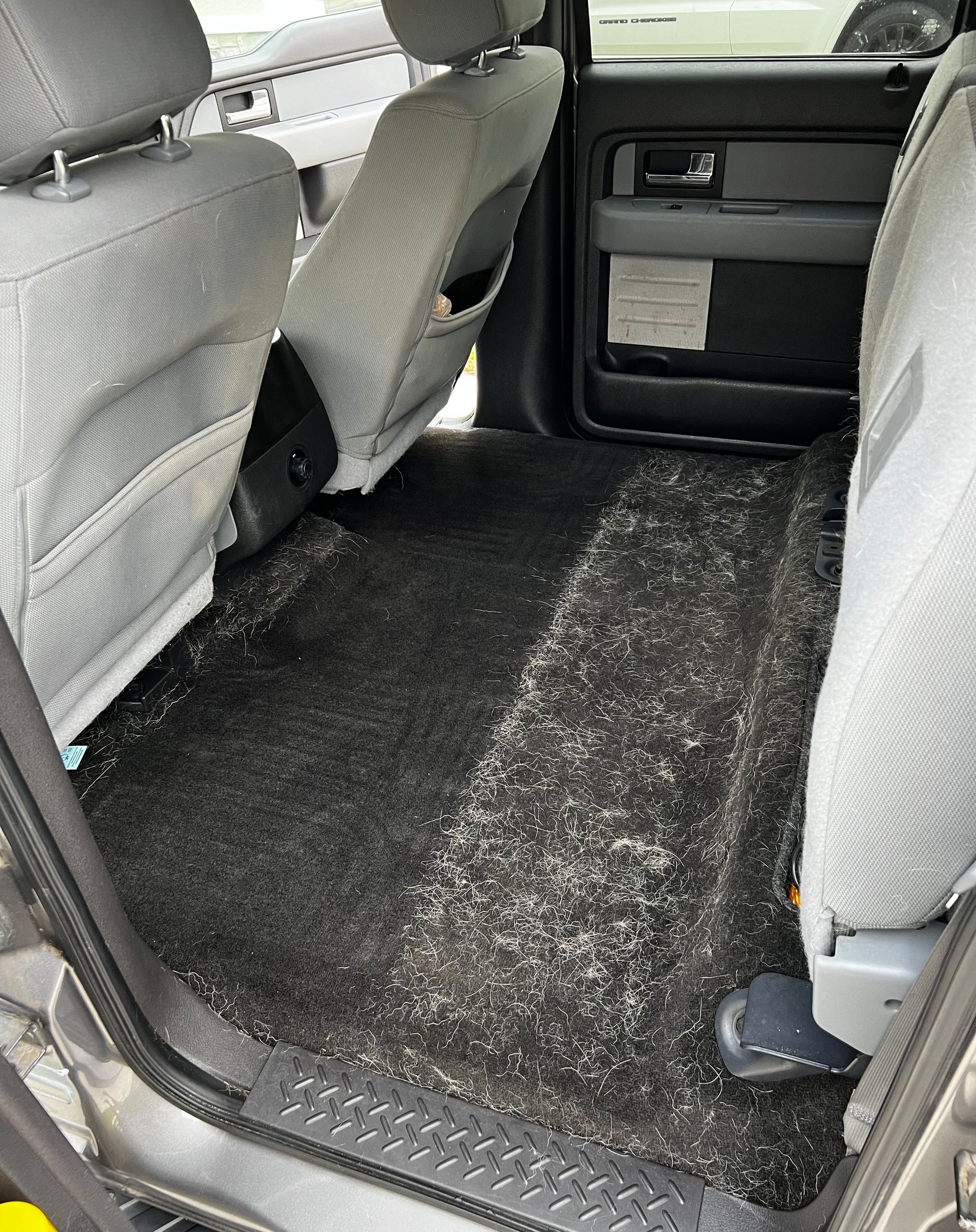 The rear seats of a car are covered in dust and dirt.