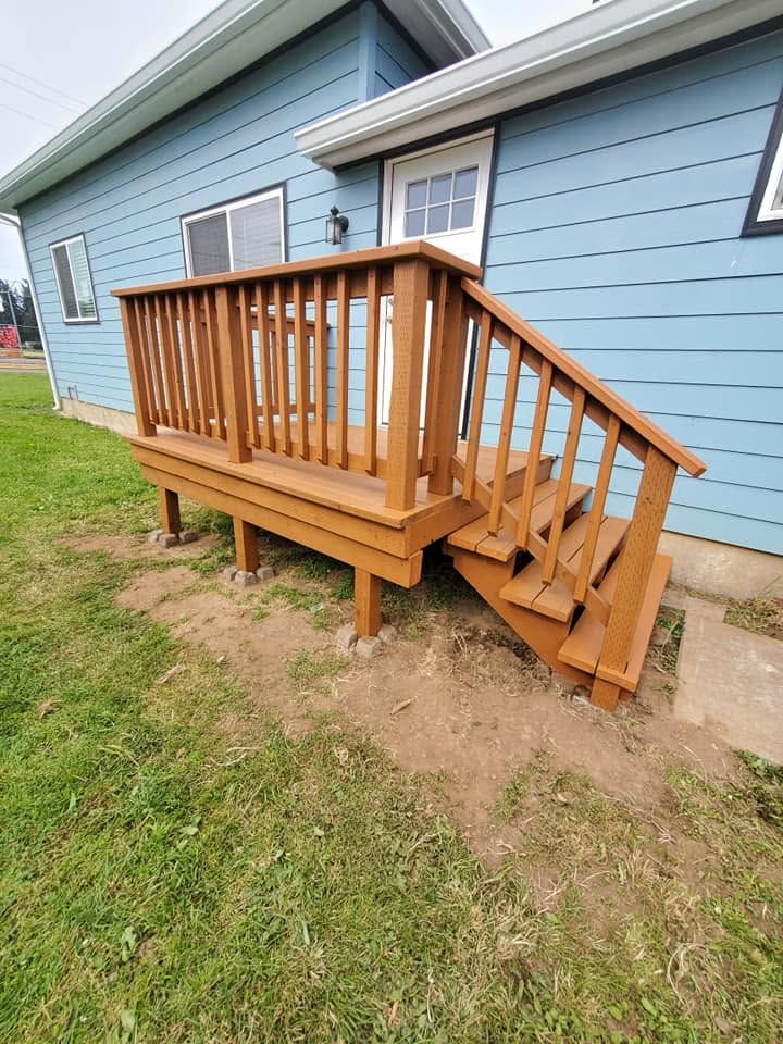 Small wooden accessibility ramp and stairs beside a light blue house with white trim.