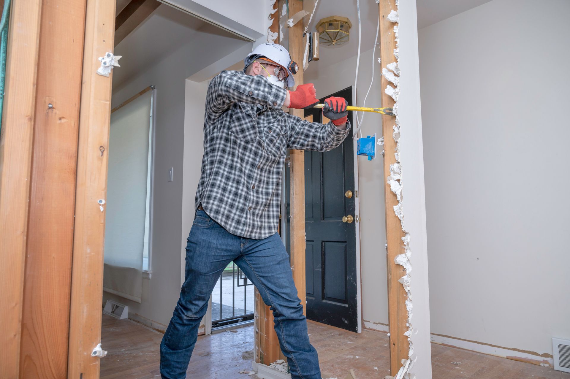 Person using a sledgehammer to remove a wall inside a home renovation site