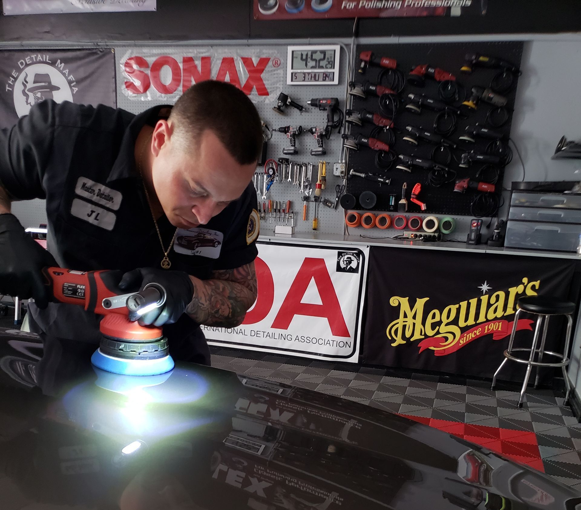 a man is polishing a car with a sonax sign in the background