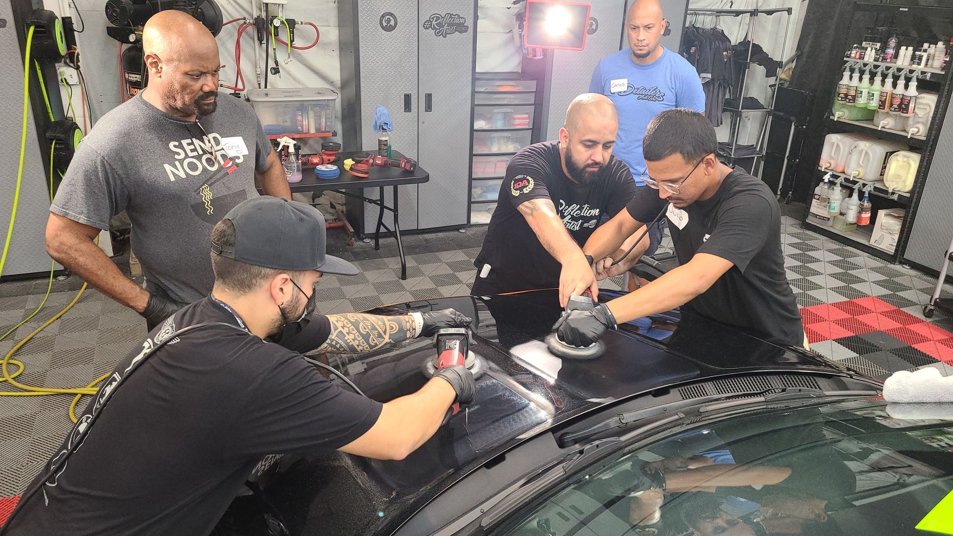 A group of men are working on a car in a garage.