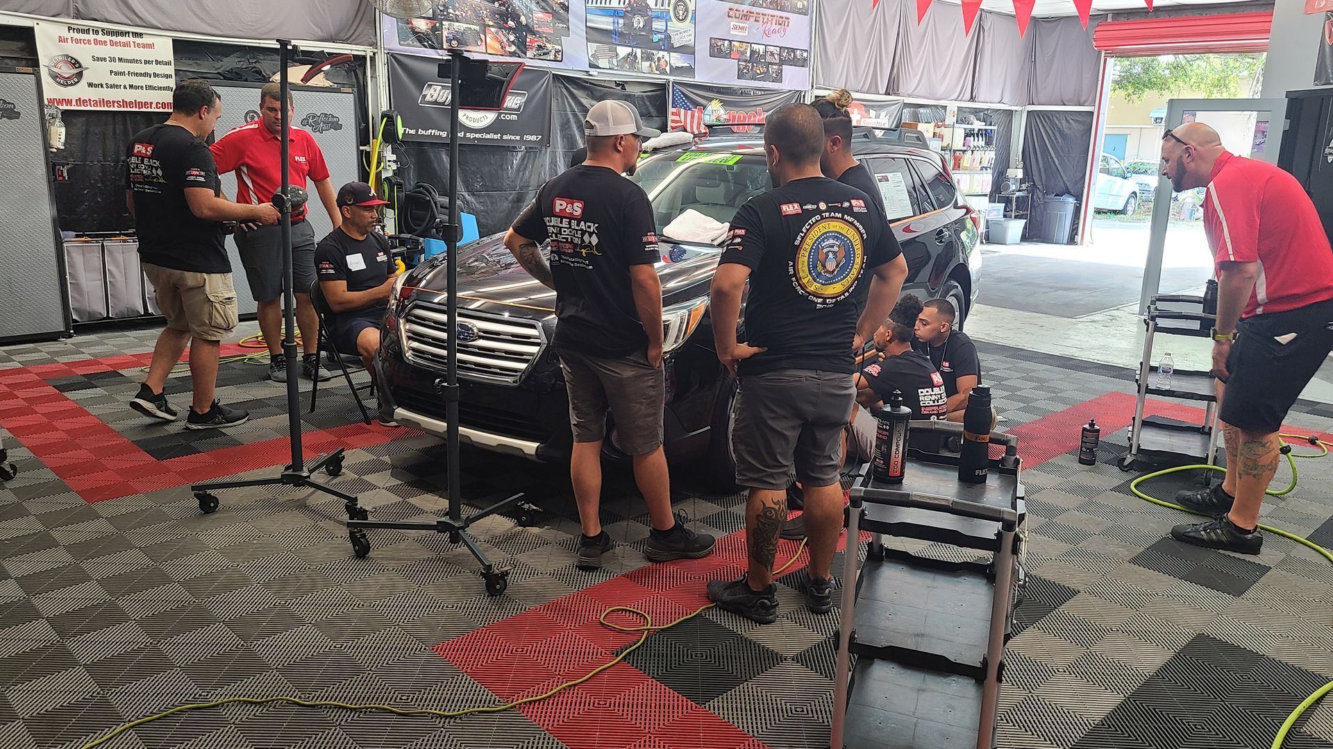 A group of men are standing around a car in a garage.