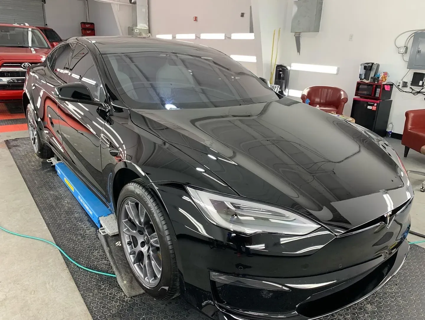 Black sports sedan in a garage, viewed from the front-left side.