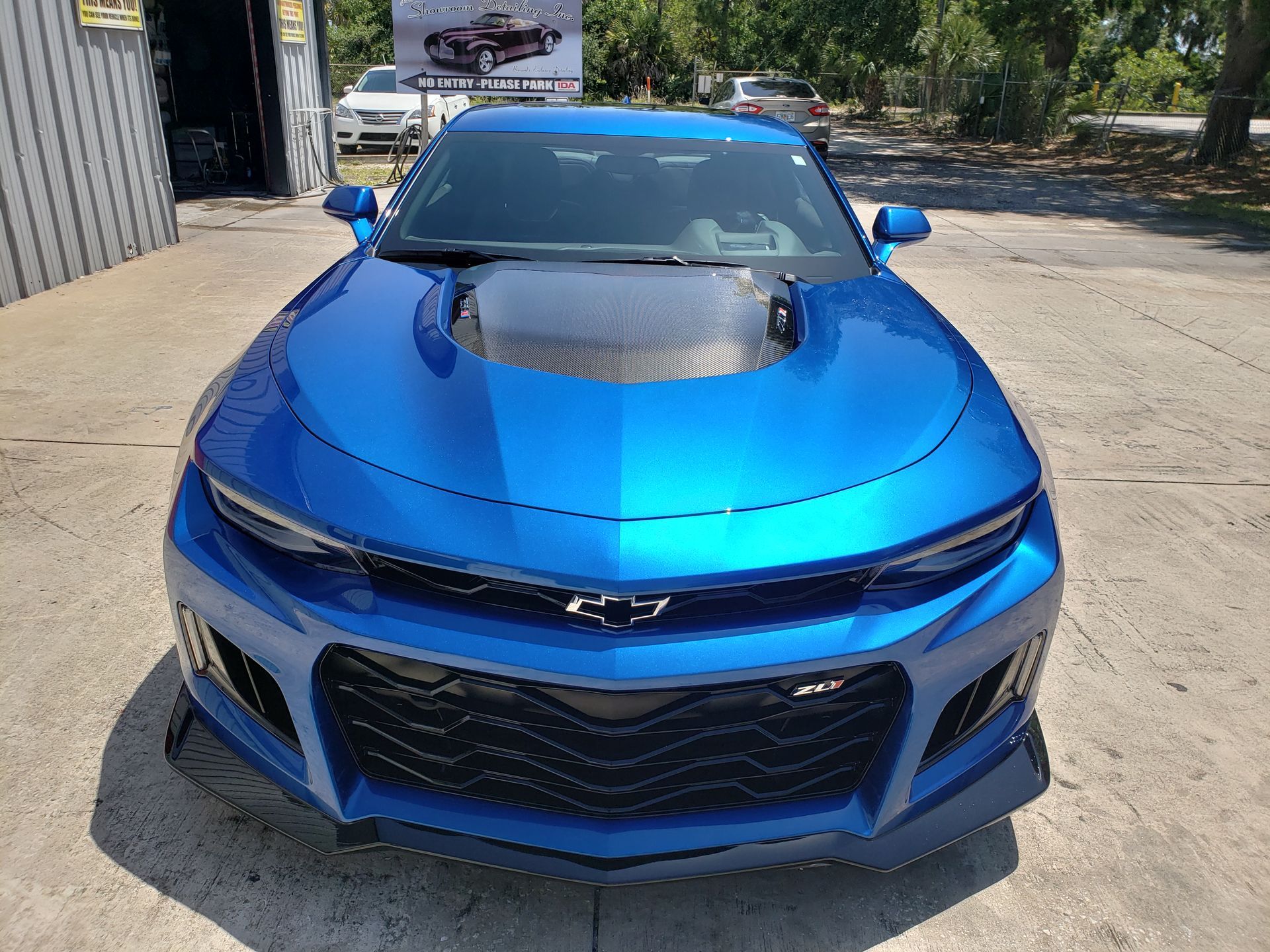 A blue chevrolet camaro is parked in front of a garage.