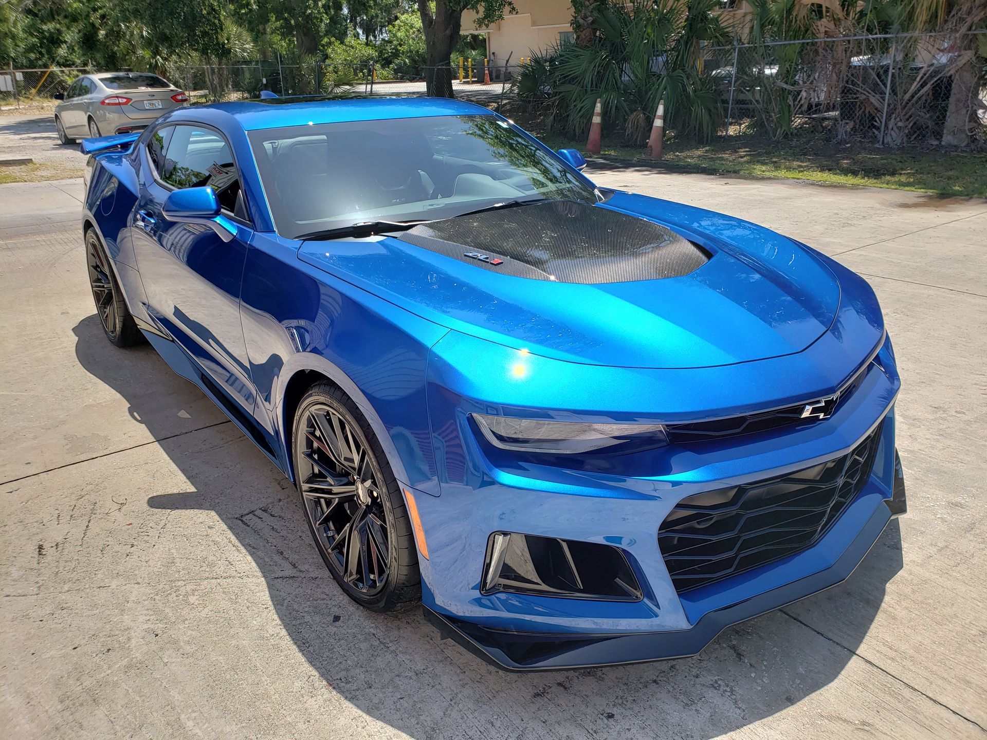 Blue sports car parked on a sunny street, angled front view