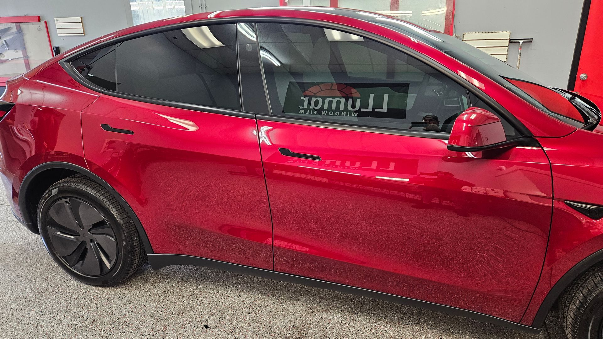 Red compact SUV parked indoors with red body and black wheels, side view