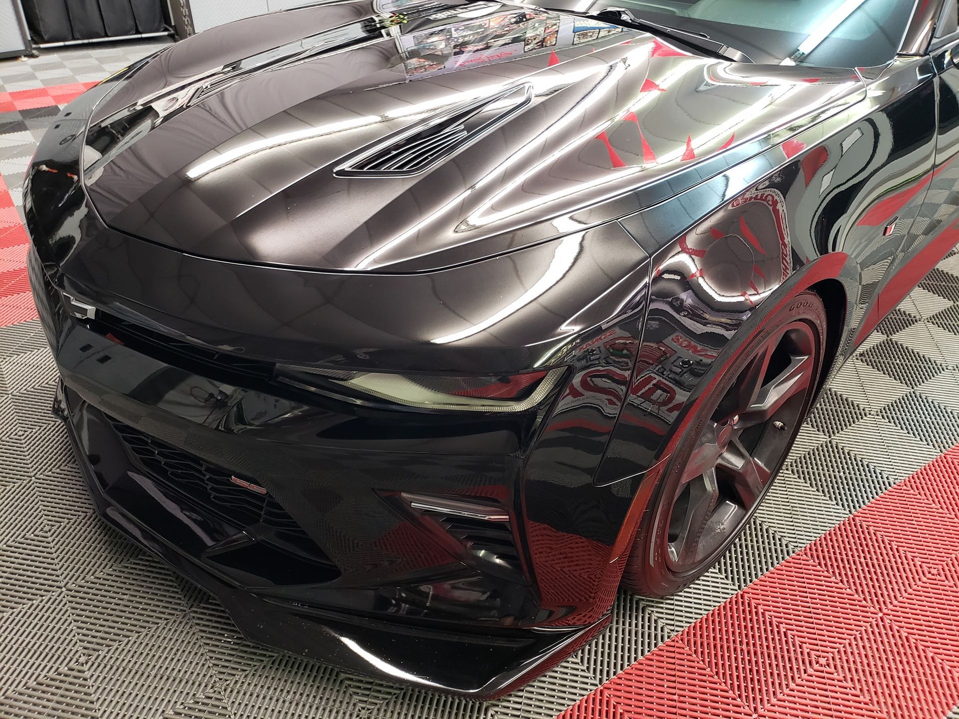Black, glossy sports car front with visible hood vents and a custom lower spoiler.
