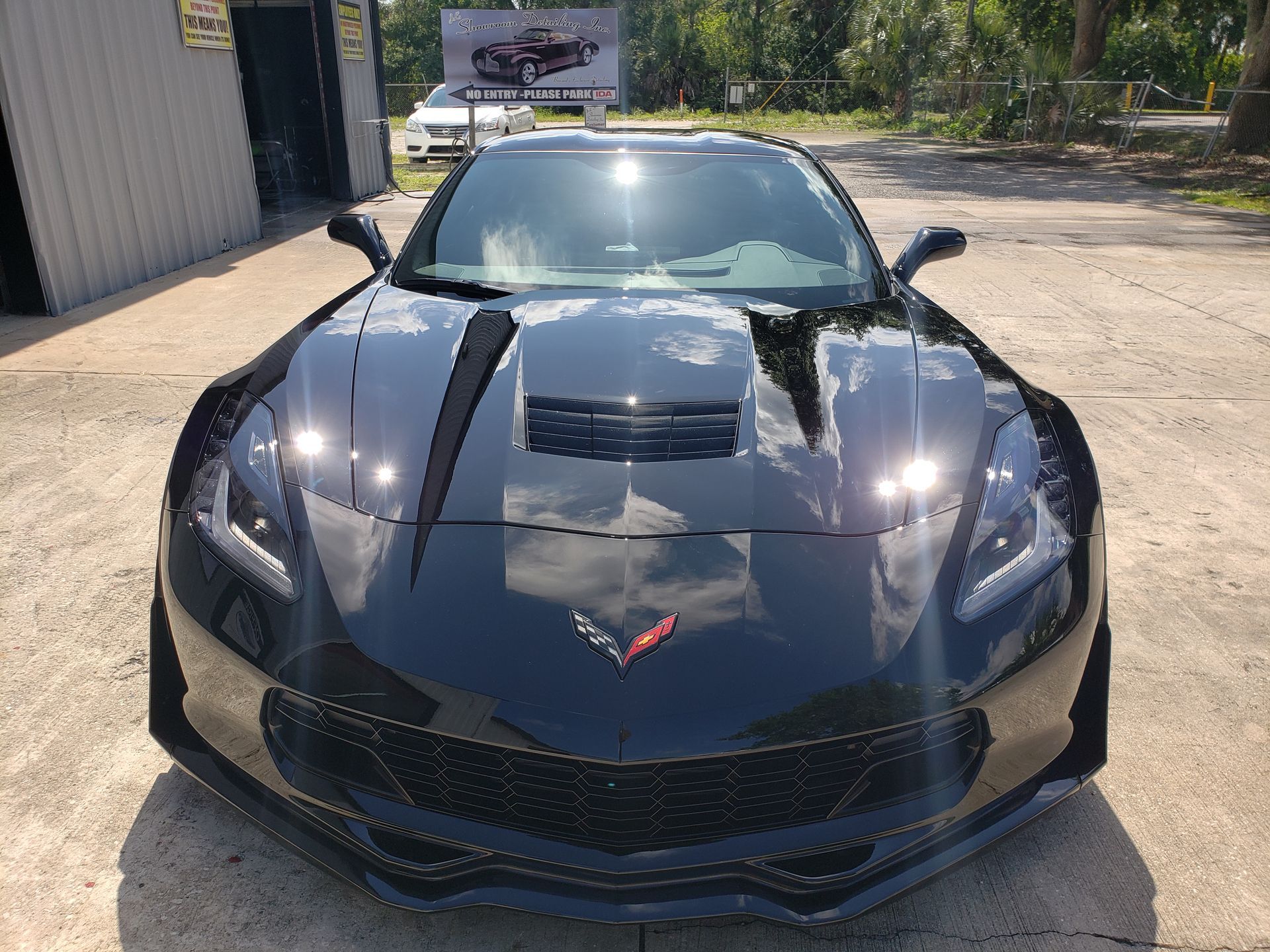 A black corvette is parked in a parking lot in front of a building.