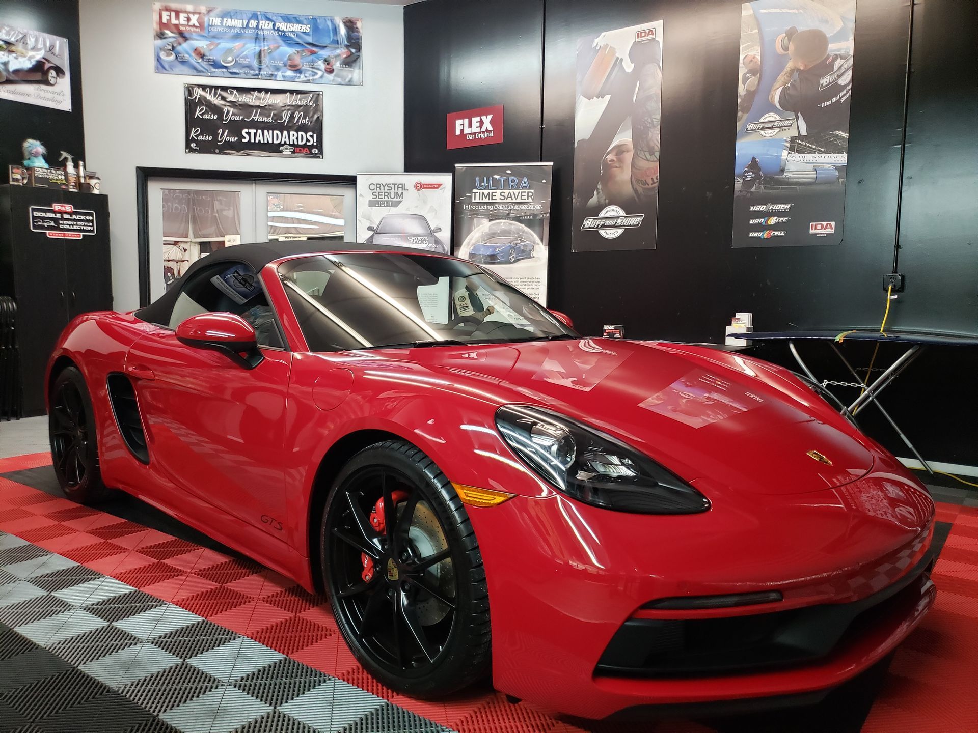 Red sports car in a showroom with black walls and posters