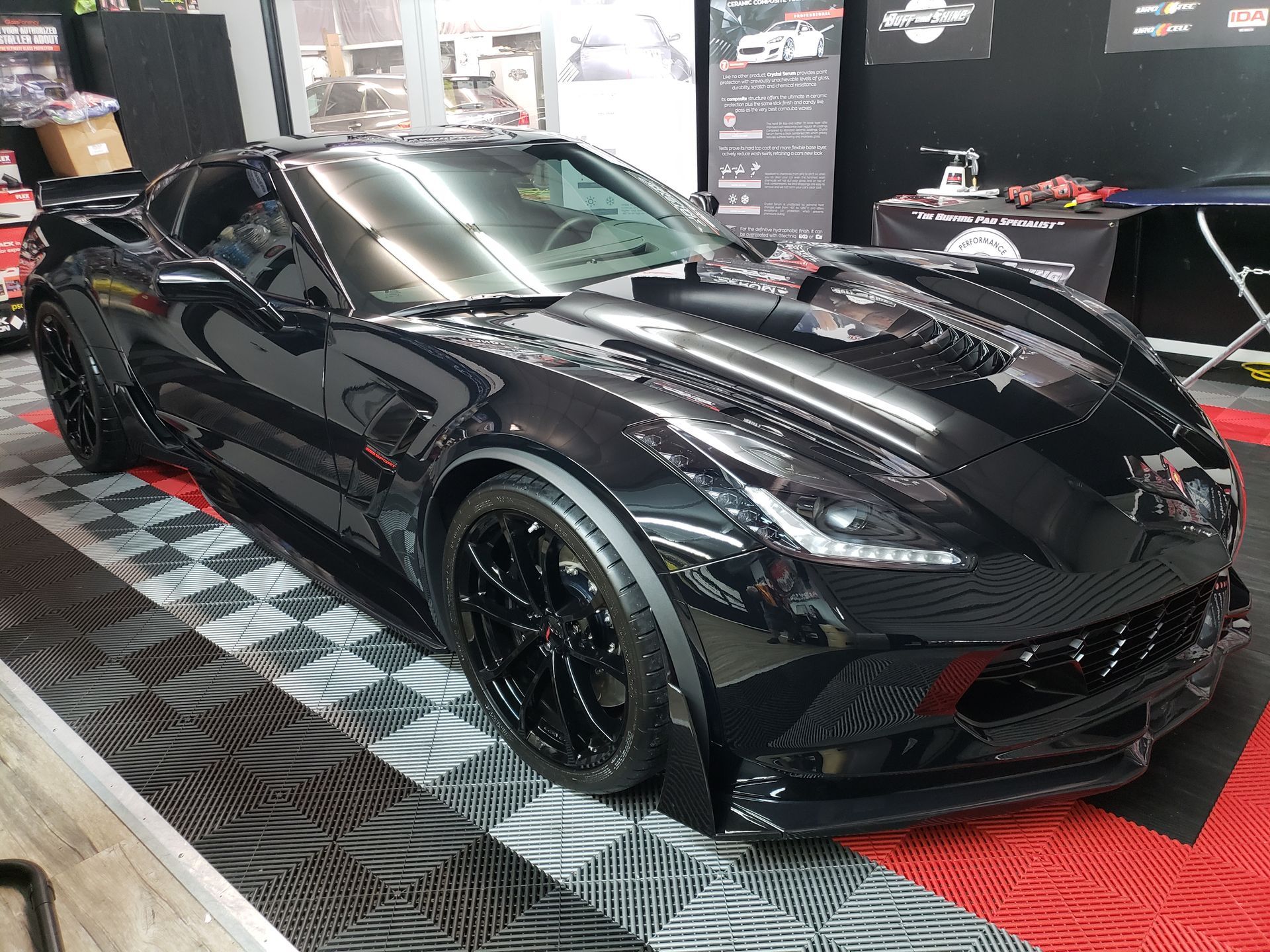 Black sports car on display in an indoor showroom, viewed from the front-left side.