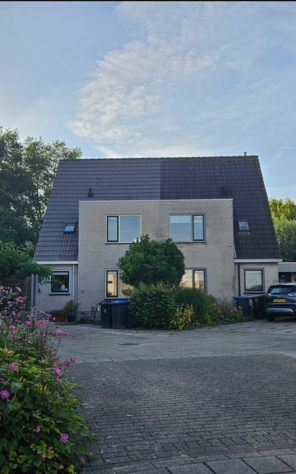 Een huis met een zwart dak en veel ramen