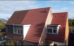 Een luchtfoto van een huis met een rood pannendak.