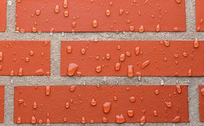 Een close-up van een bakstenen muur met waterdruppels erop.