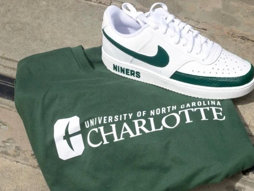 UNC Charlotte green T-shirt with white Nike sneaker on top, on a concrete surface