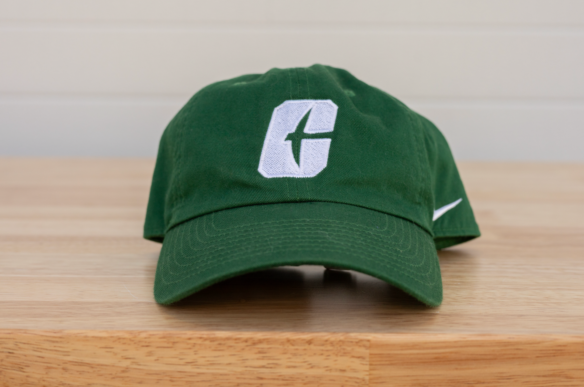 Green baseball cap with a white “G” logo on a wooden surface