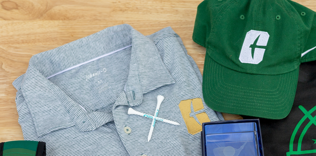 Gray striped shirt, green cap, and a smartphone laid out on a bed