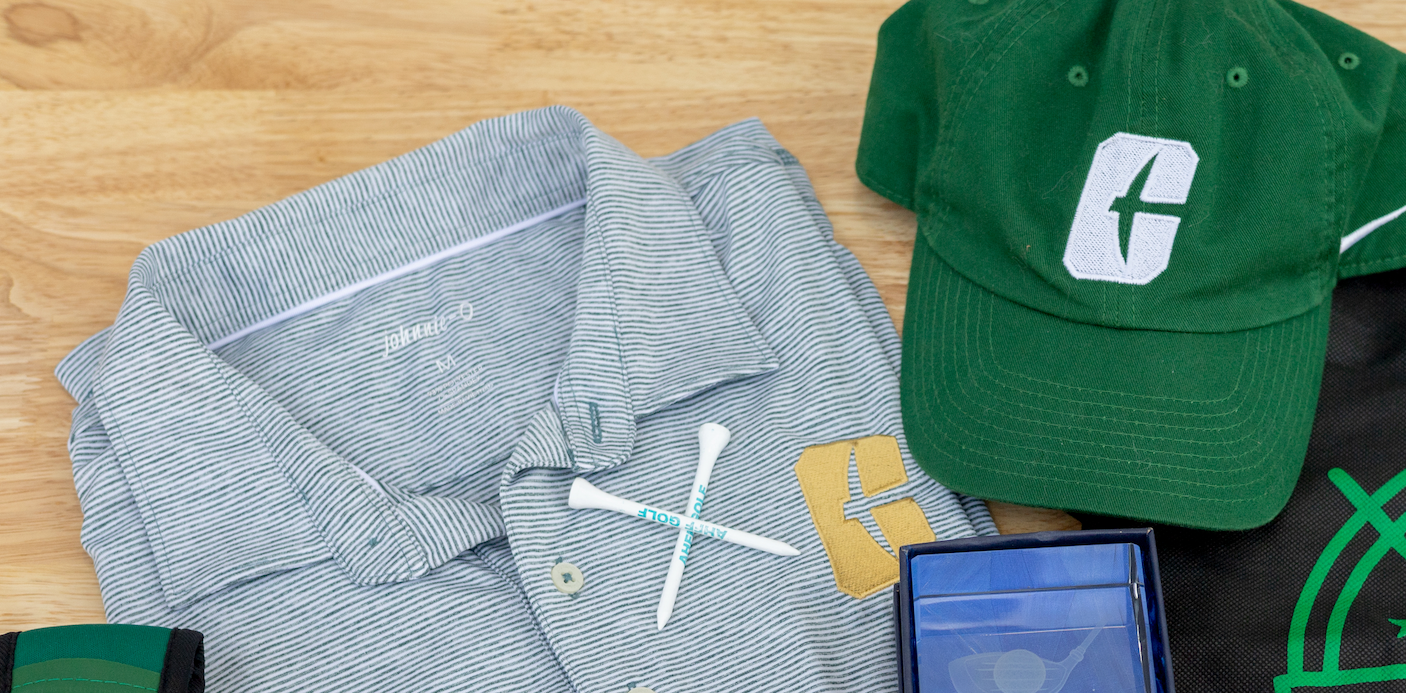Green cap and striped shirt laid out beside a blue phone on a patterned surface.