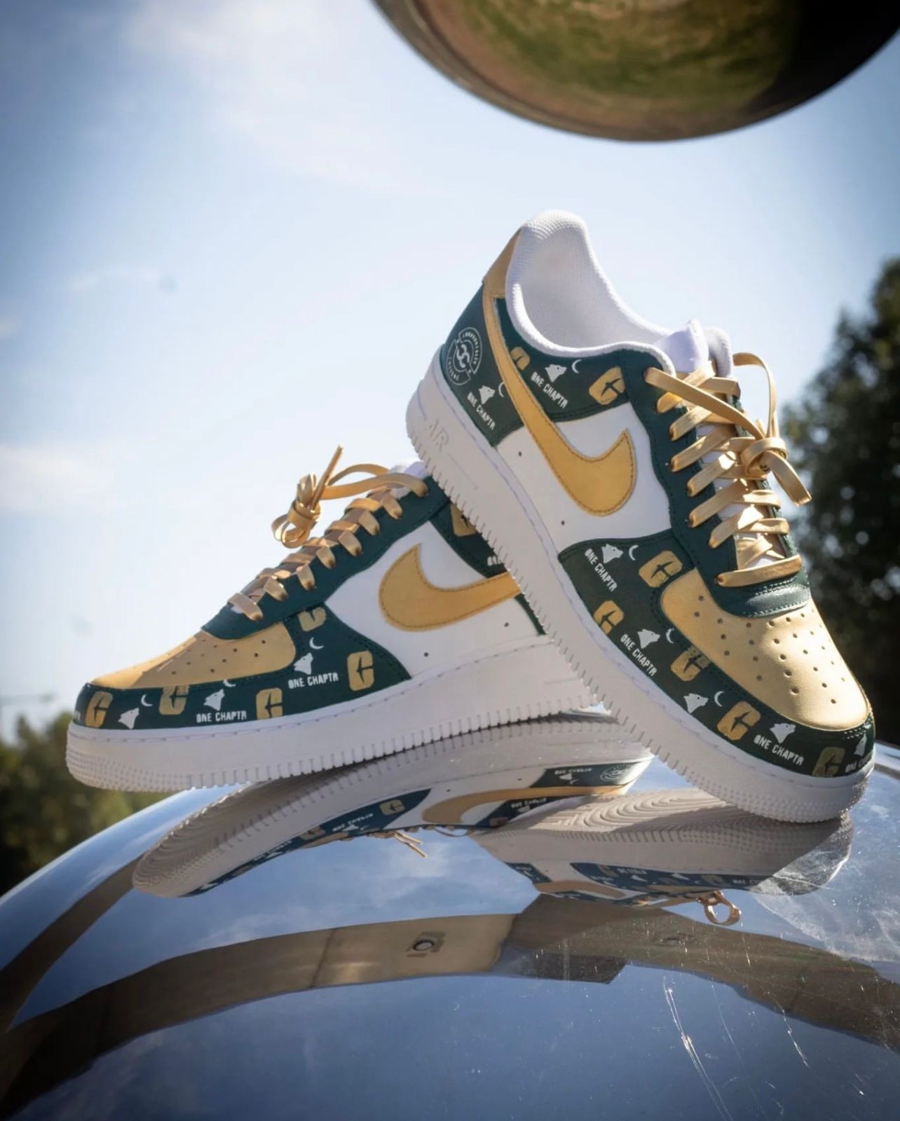 Green and gold patterned Nike sneakers on a reflective surface outdoors under a bright sky