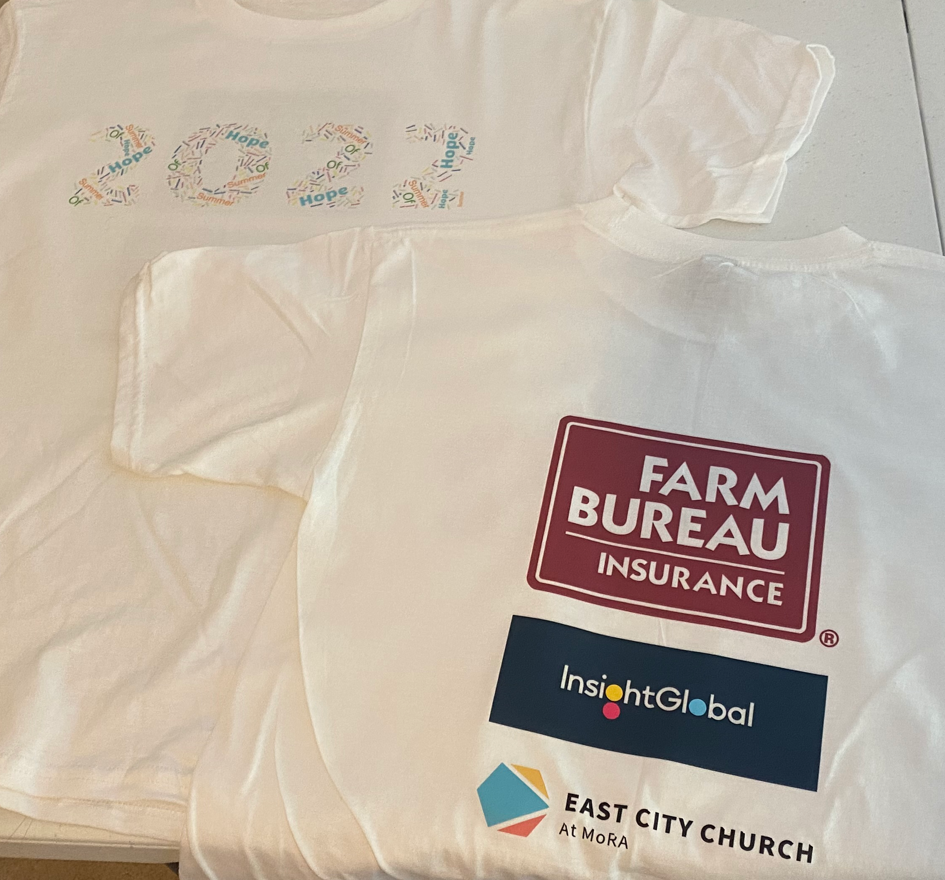 White T-shirts with colorful 2024 print and sponsor logos: Farm Bureau Insurance, Insight Global, East City Church