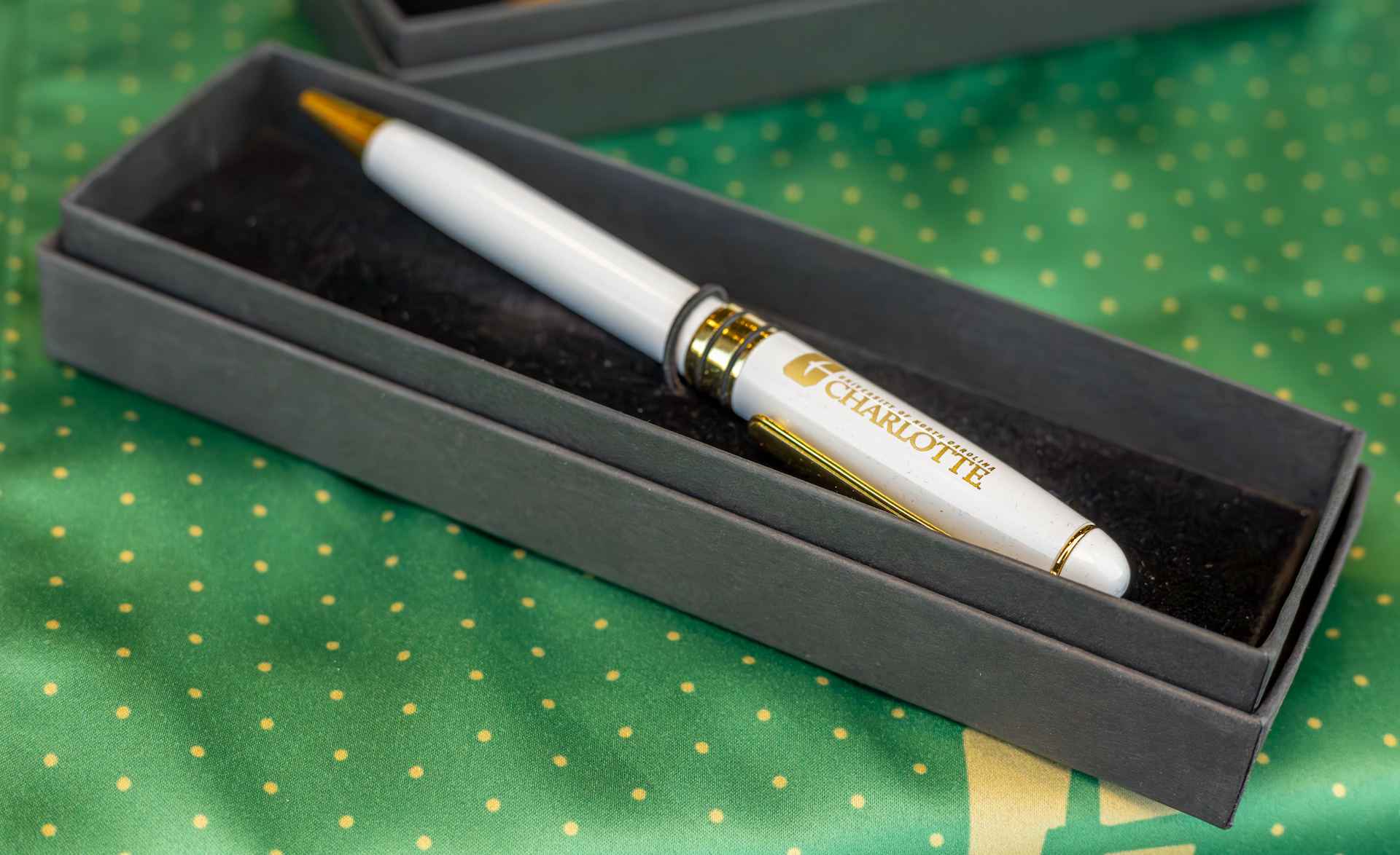 White pen with gold accents in a black presentation box on a green patterned surface