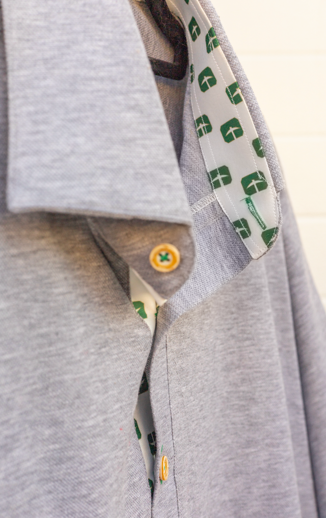 Close-up of a gray shirt collar with a patterned inner lining and yellow-green button detail