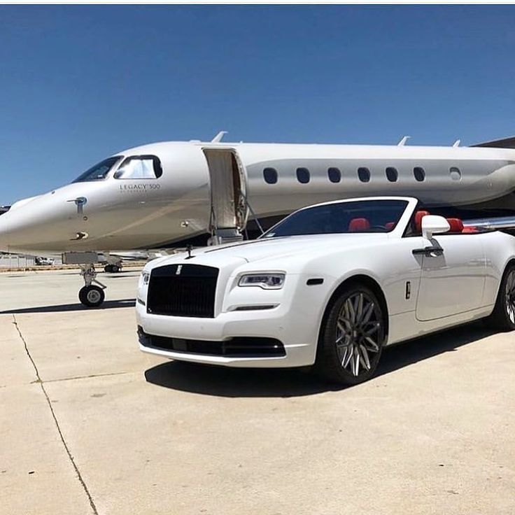 White Rolls-Royce convertible parked in front of a private jet on a sunny tarmac.