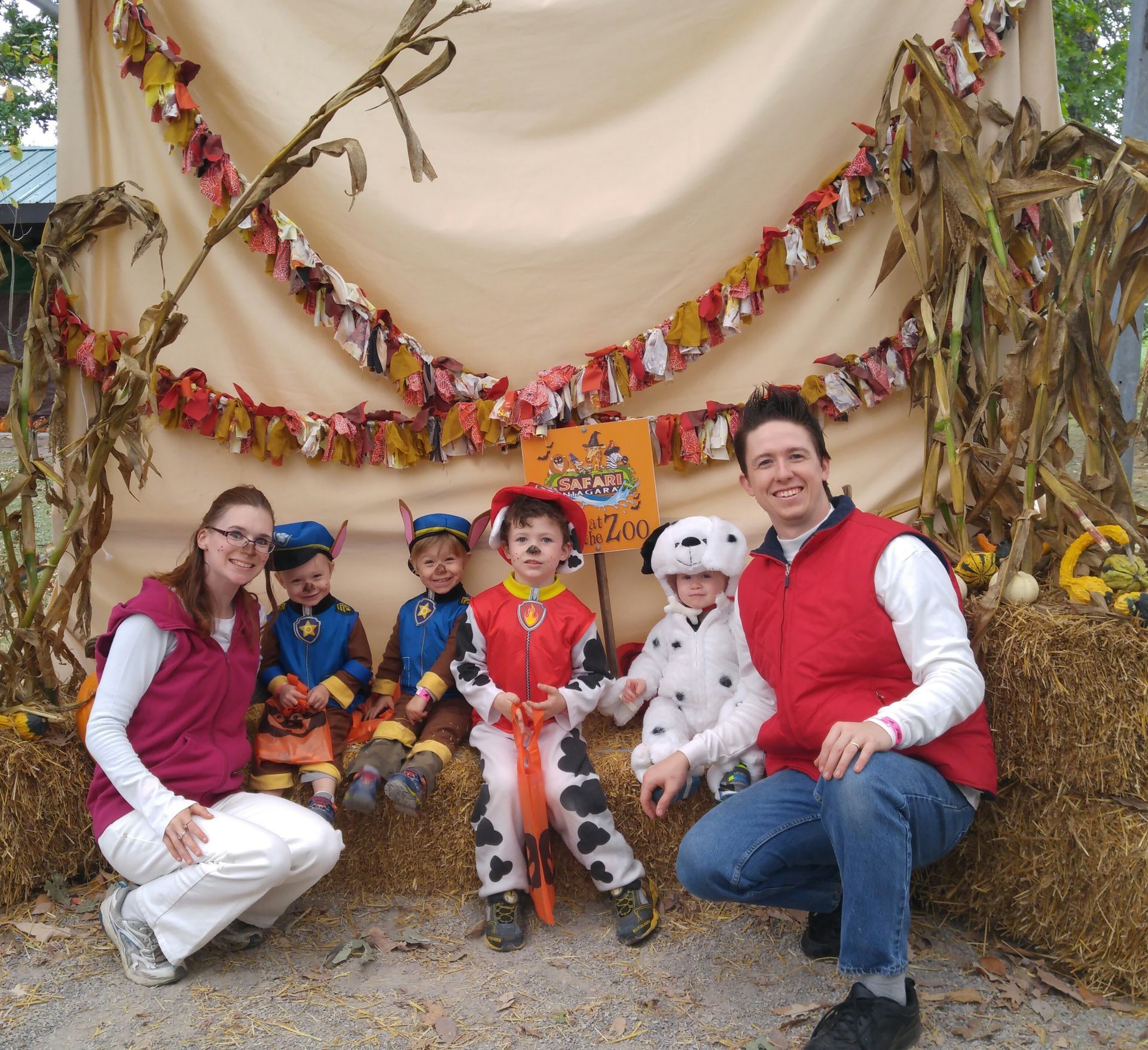 a family posing for a picture in front of a sign that says boo at the zoo at a safari adventure niagara
