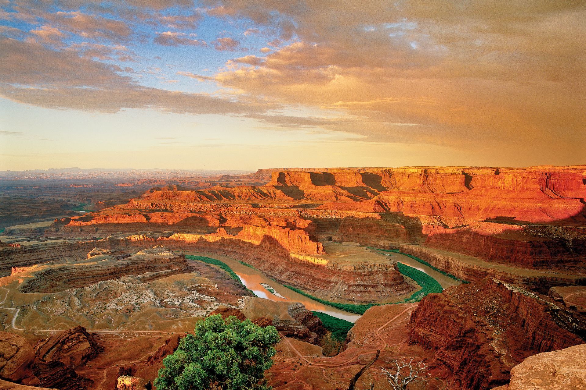 Canyonlands National Park at sunset, orange and red rock formations with a green river winding through the canyon.