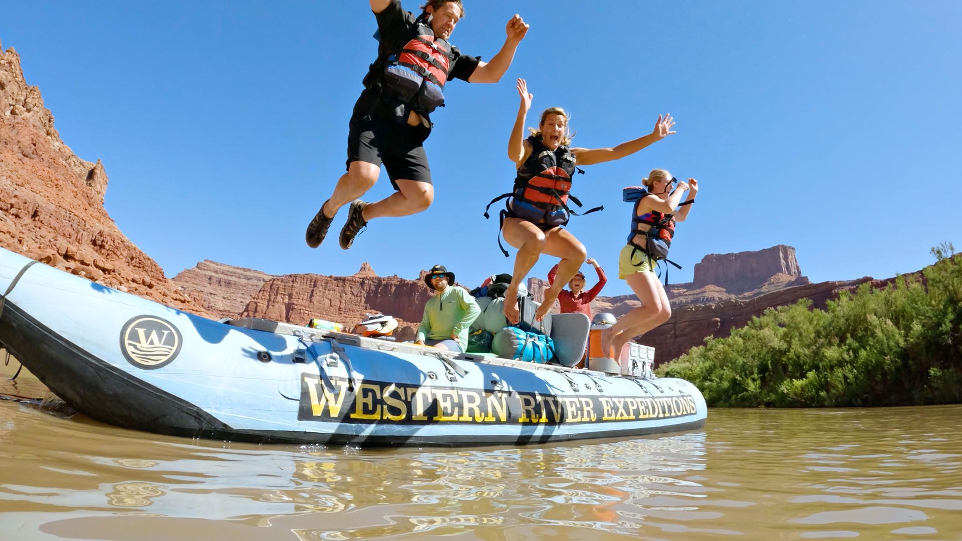 Family jumping from a raft on the Colorado River.